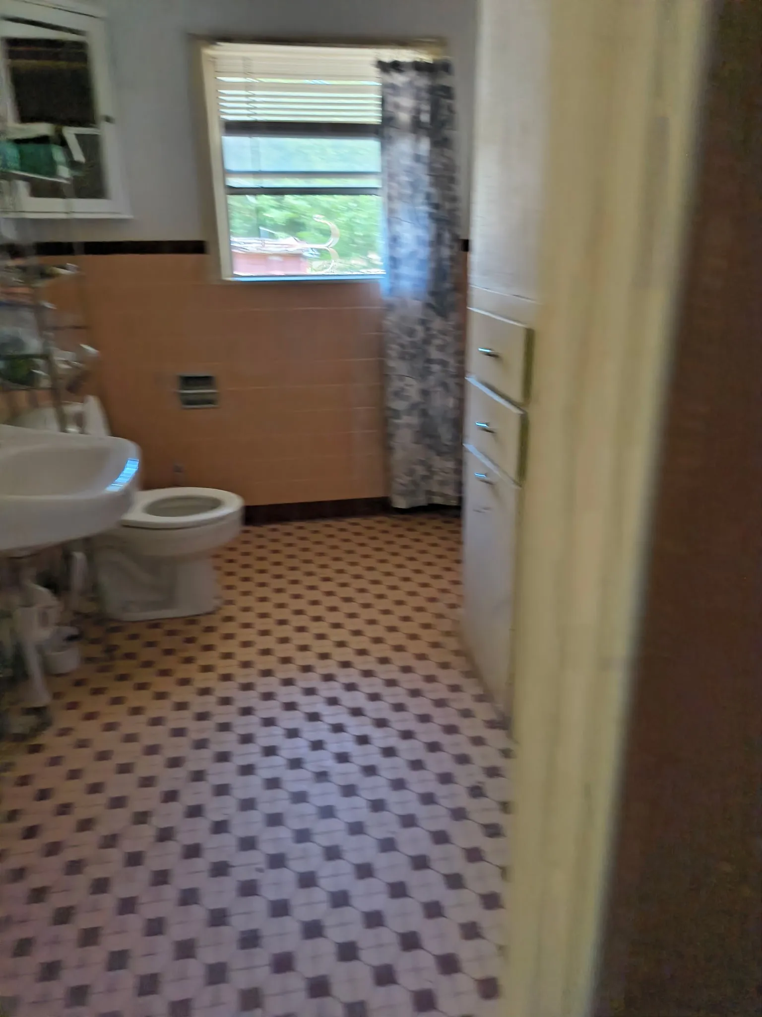 Bathroom featuring patterned floor tiling, ceramic wall tiling, window with blinds, and built-in cabinetry