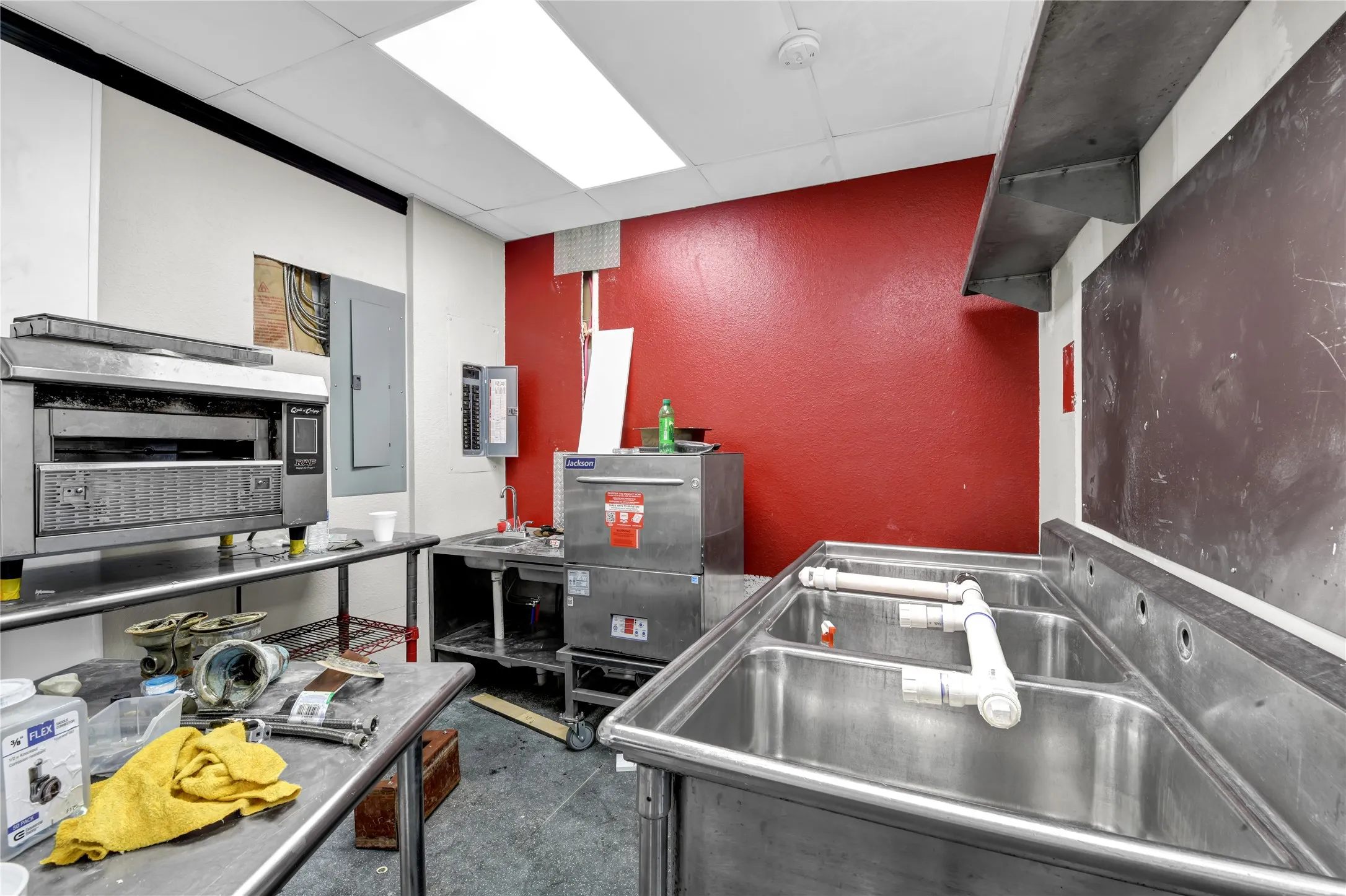 Kitchen with a paneled ceiling, electric panel, and a textured wall