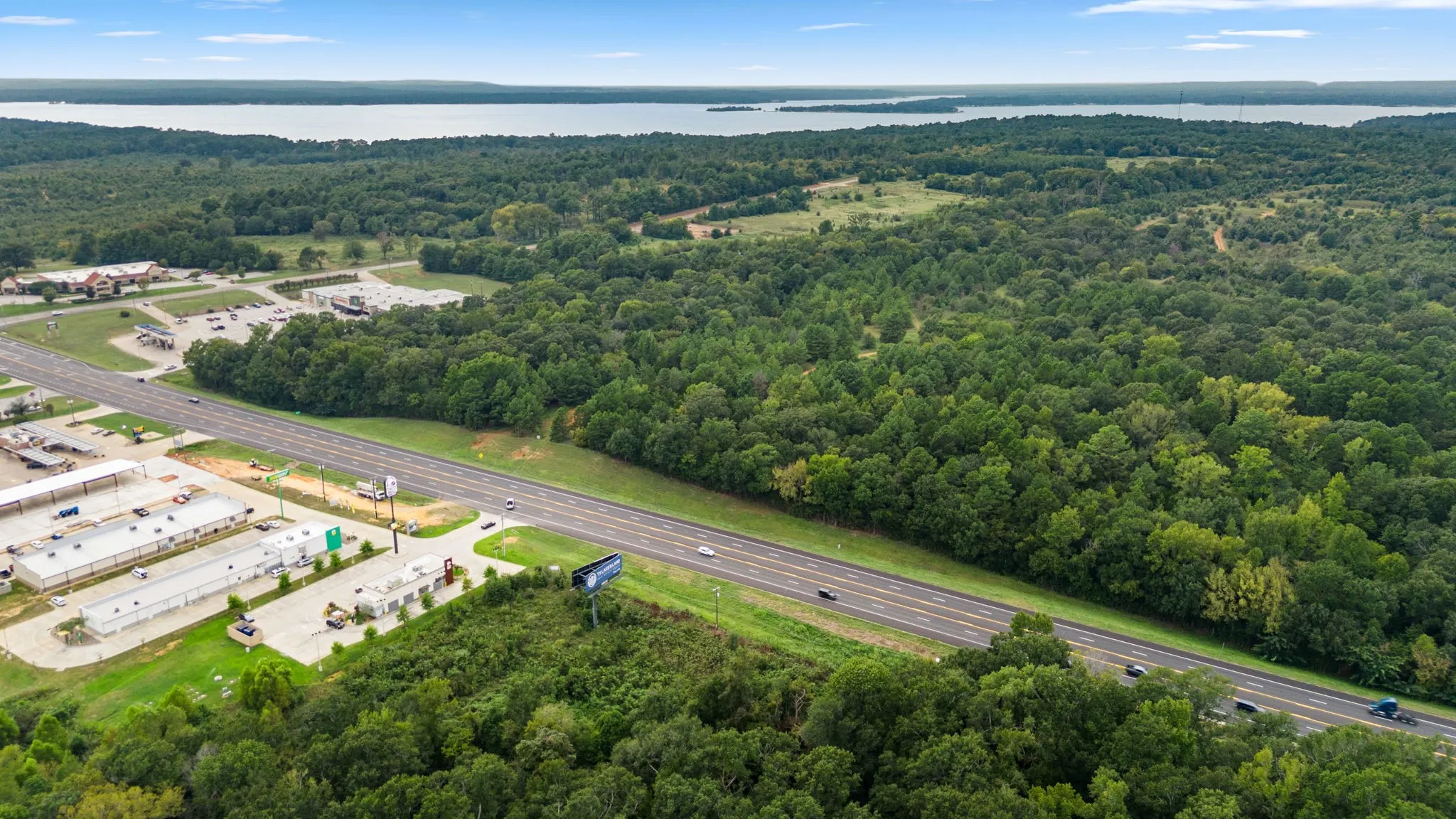 Drone / aerial view of a heavily wooded area and a nearby body of water