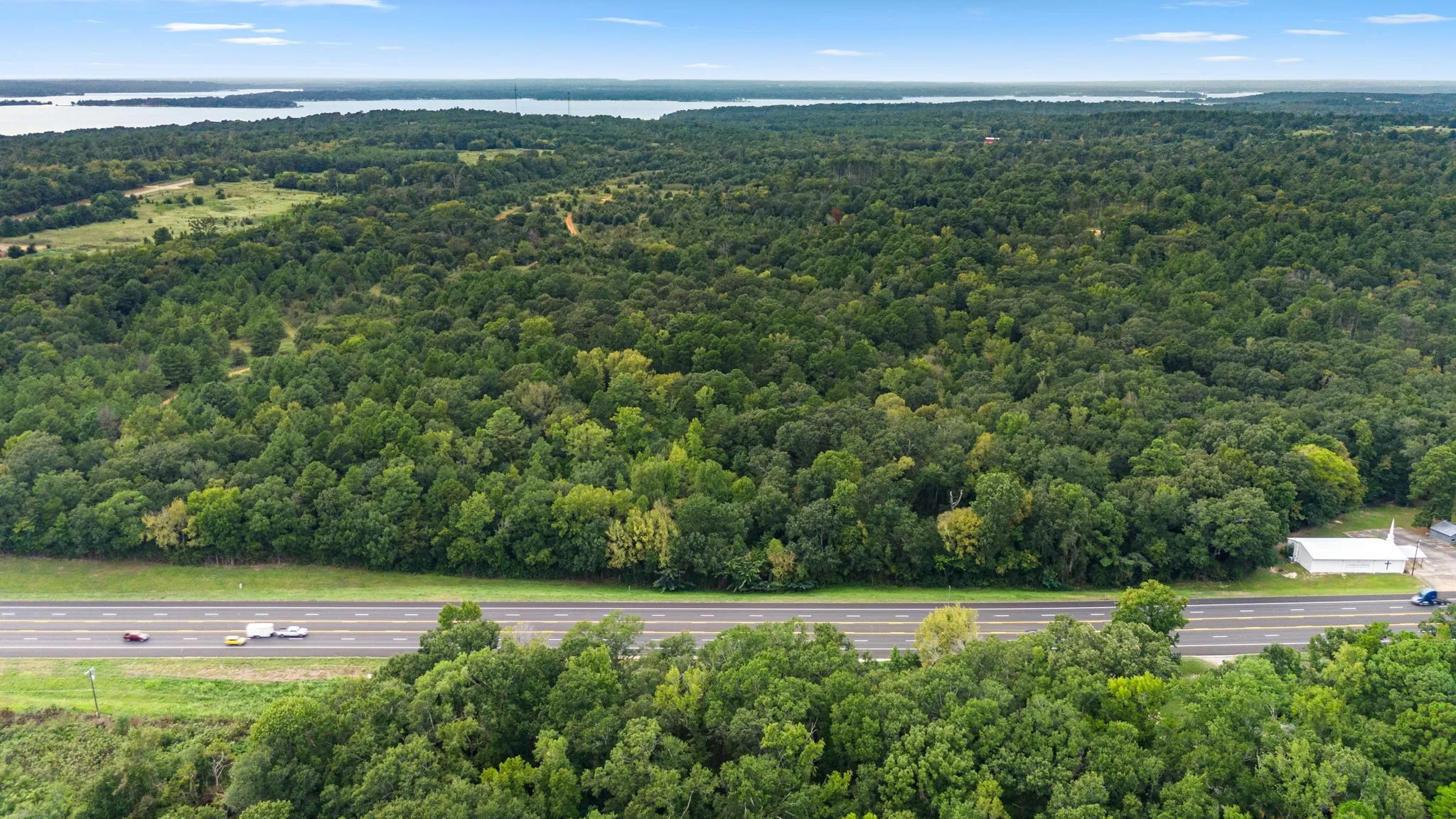 Aerial view of a heavily wooded area and a nearby body of water