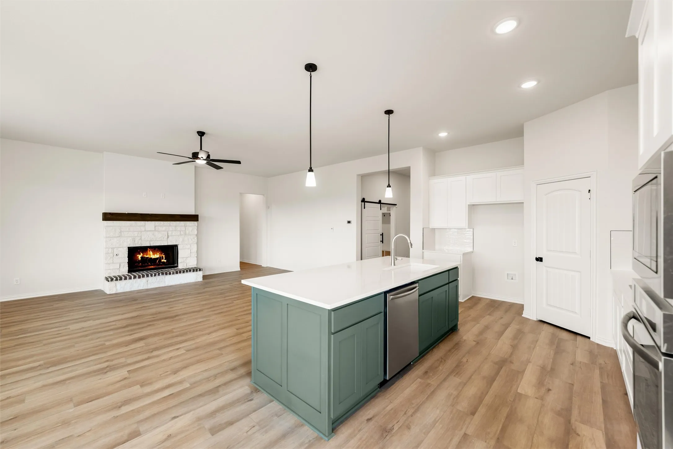 Kitchen featuring dual tone cabinetry, a fireplace, light wood finished floors, open floor plan, and a ceiling fan