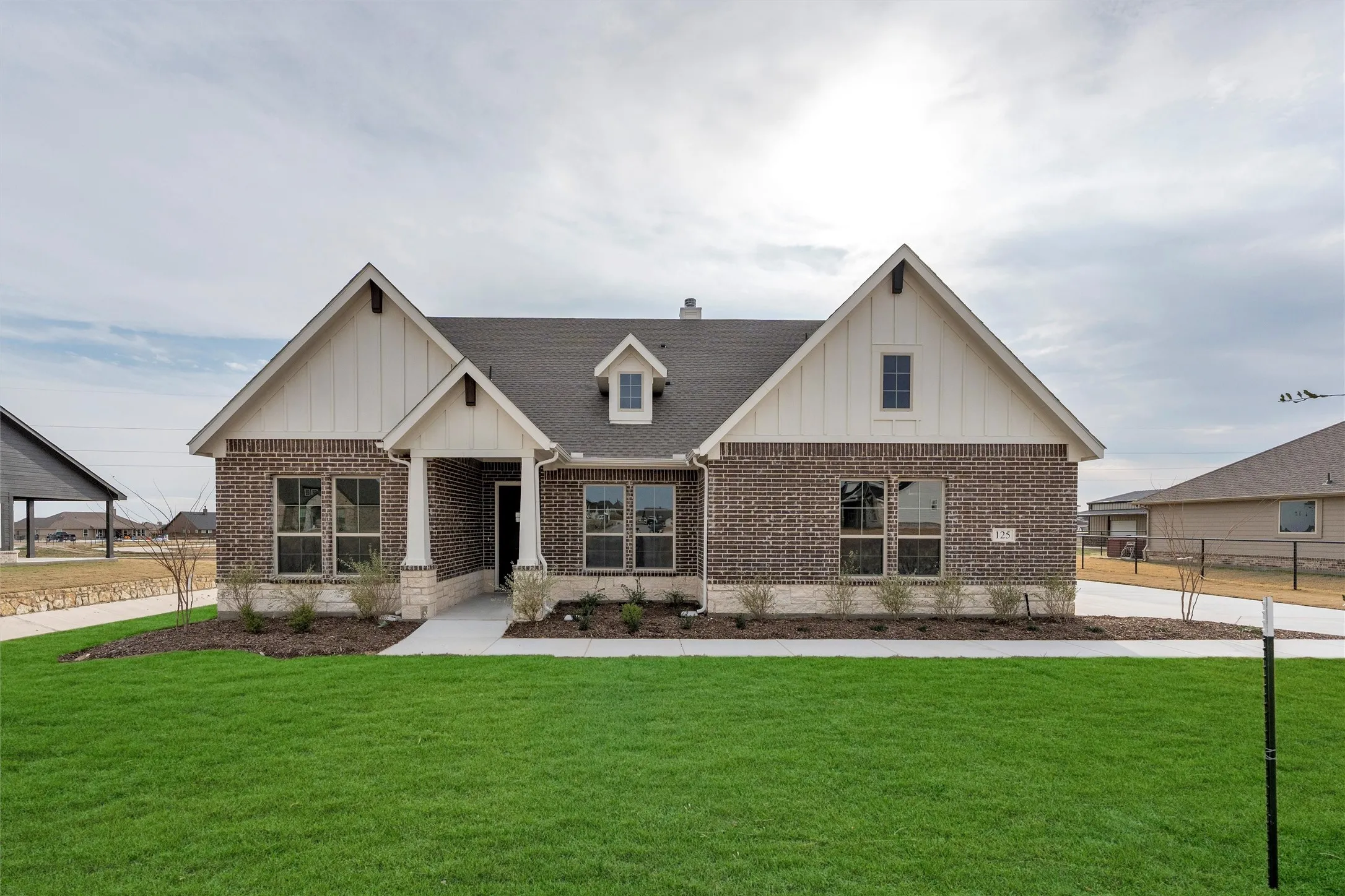 Modern farmhouse with board and batten siding, brick siding, and roof with shingles