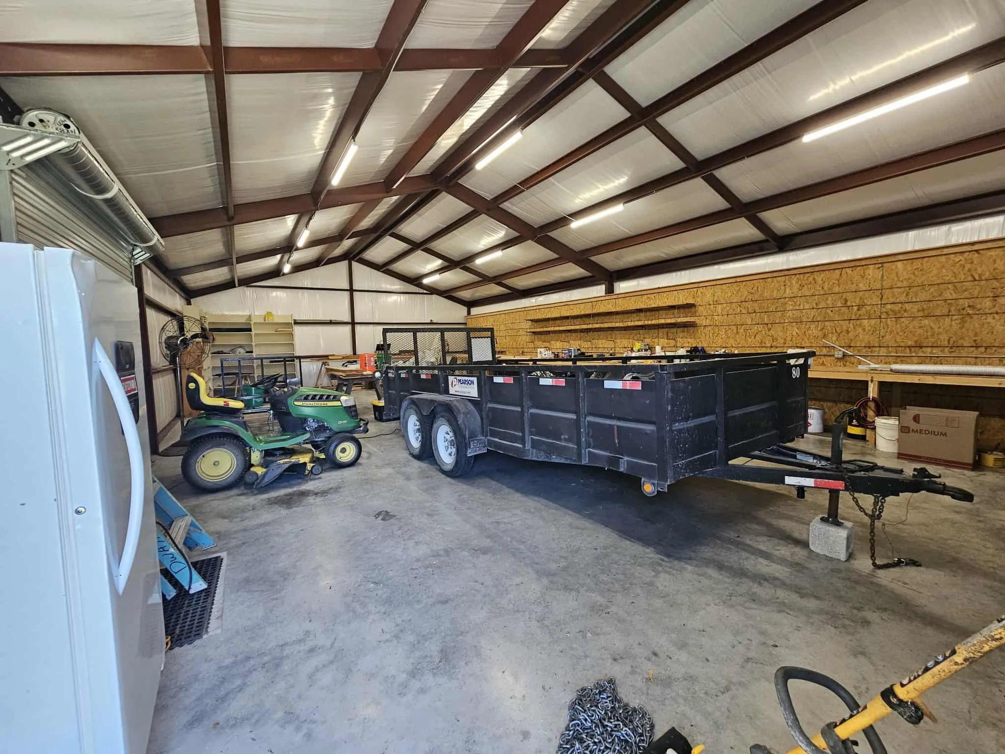Garage featuring freestanding refrigerator and metal wall