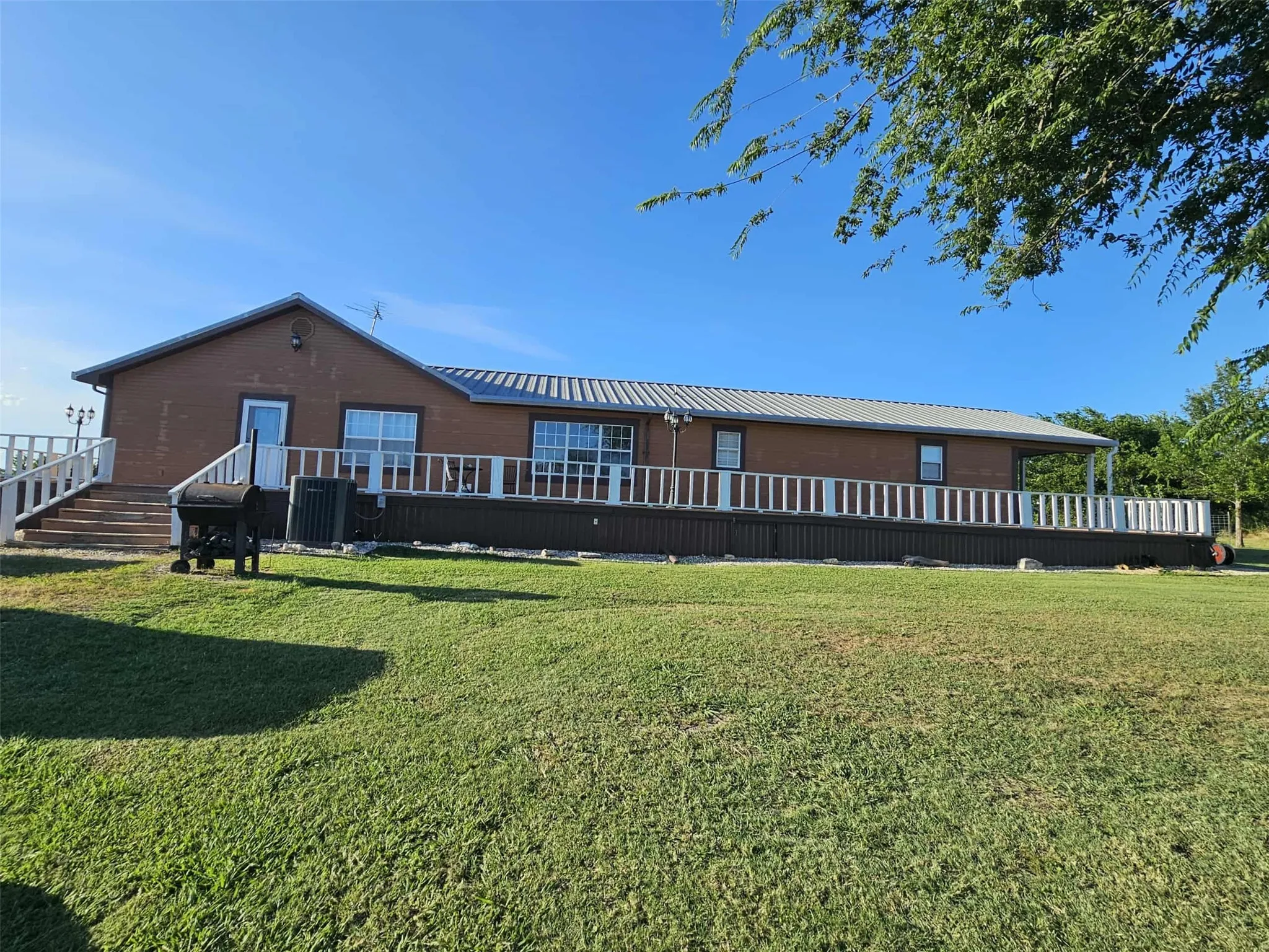 Back of house featuring a lawn, a metal roof, and a deck