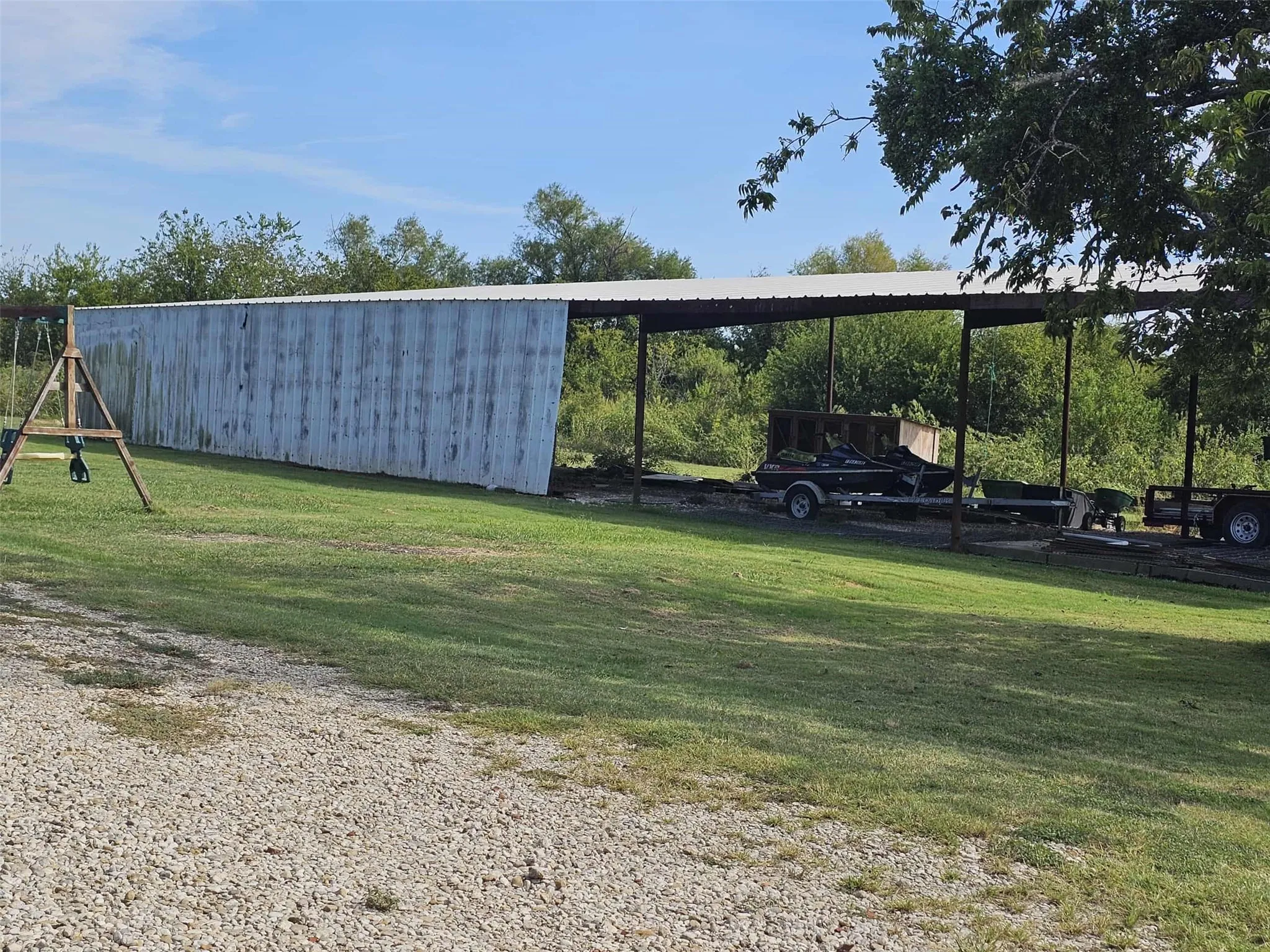 View of parking / parking lot with a carport and an outbuilding