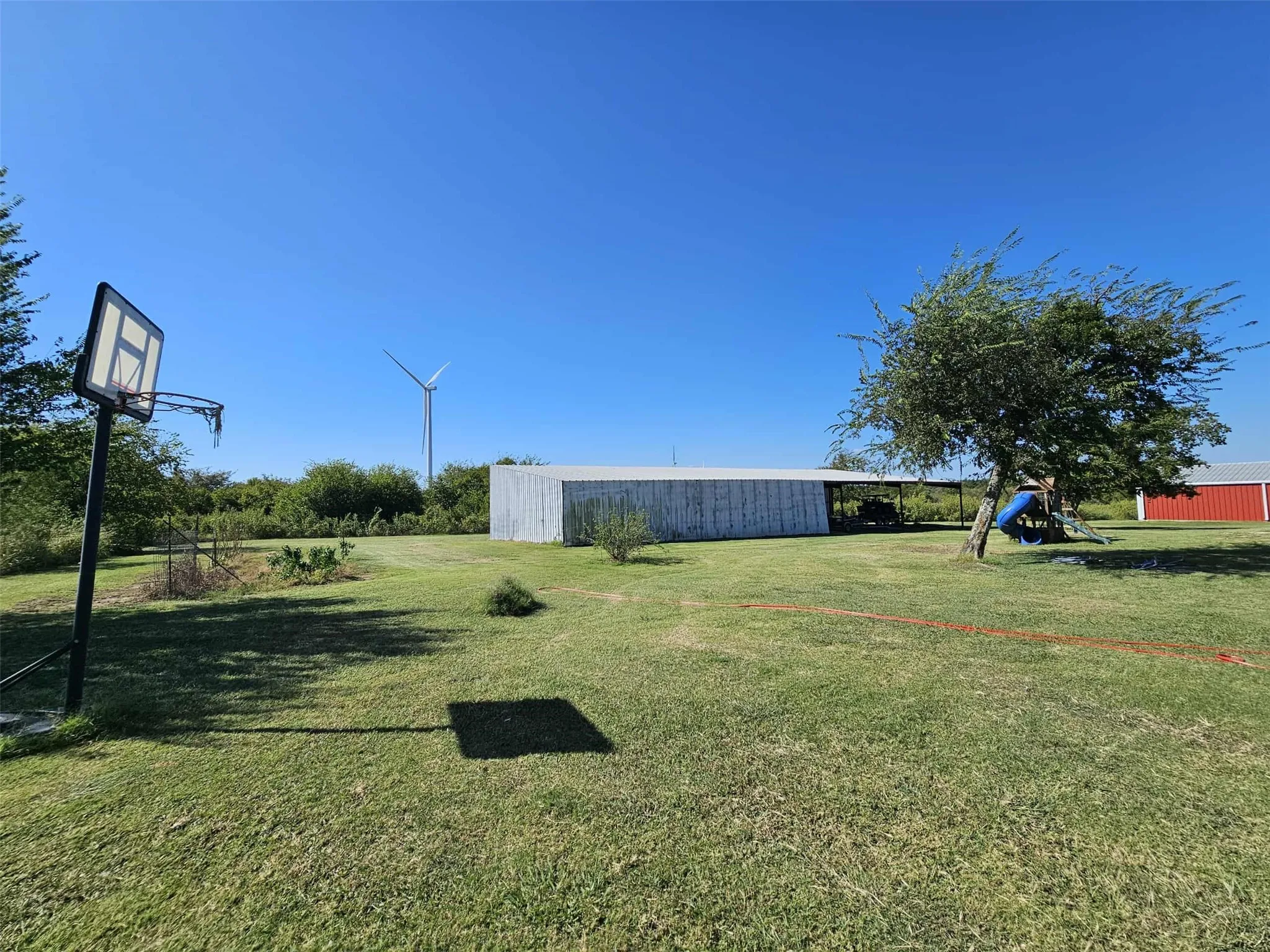 View of green lawn featuring a pole building, an outbuilding, and a playground