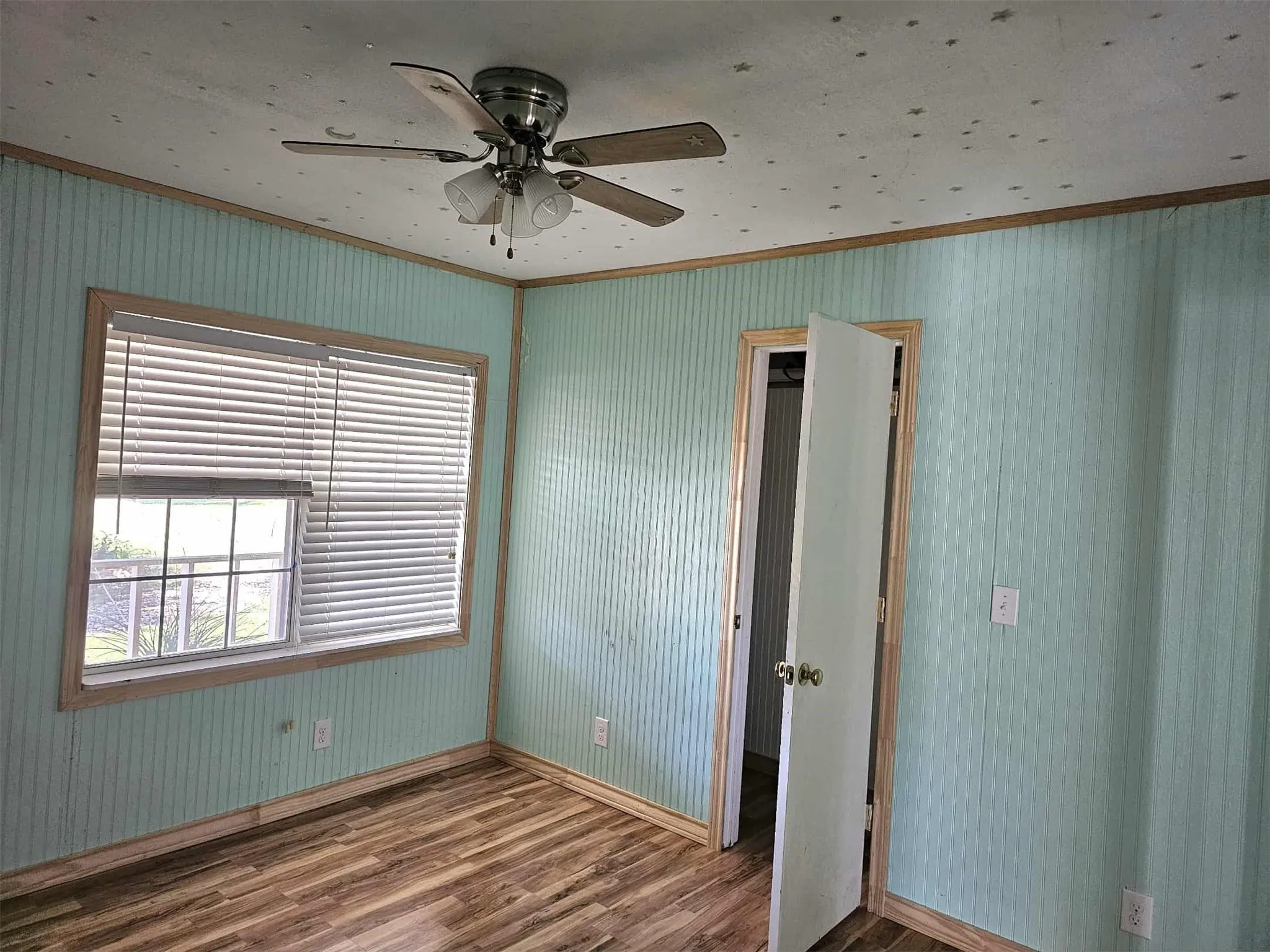 Unfurnished bedroom with ornamental molding, dark wood-type flooring, wallpapered walls, and ceiling fan