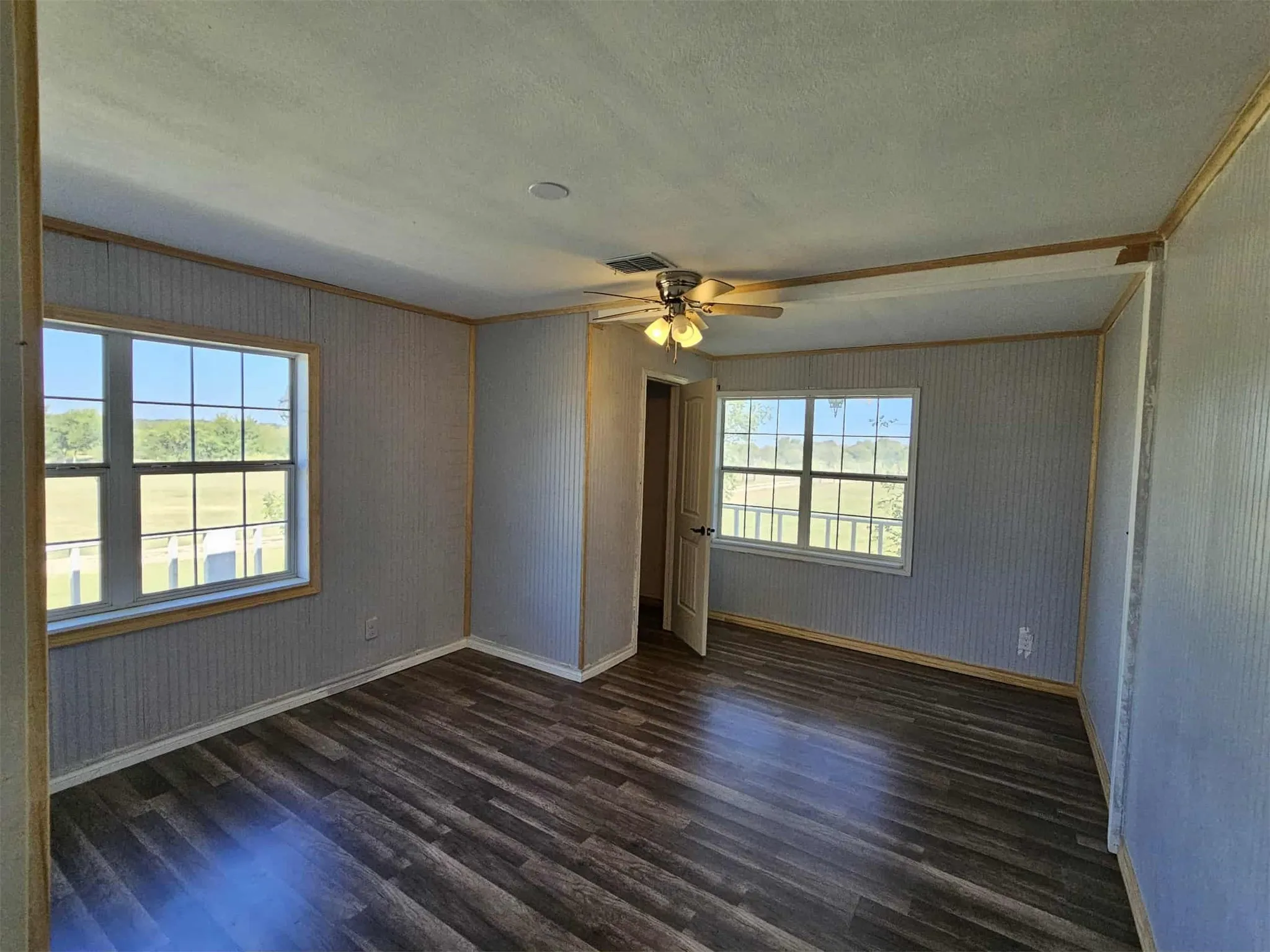 Spare room featuring dark wood finished floors, crown molding, a textured ceiling, and a ceiling fan