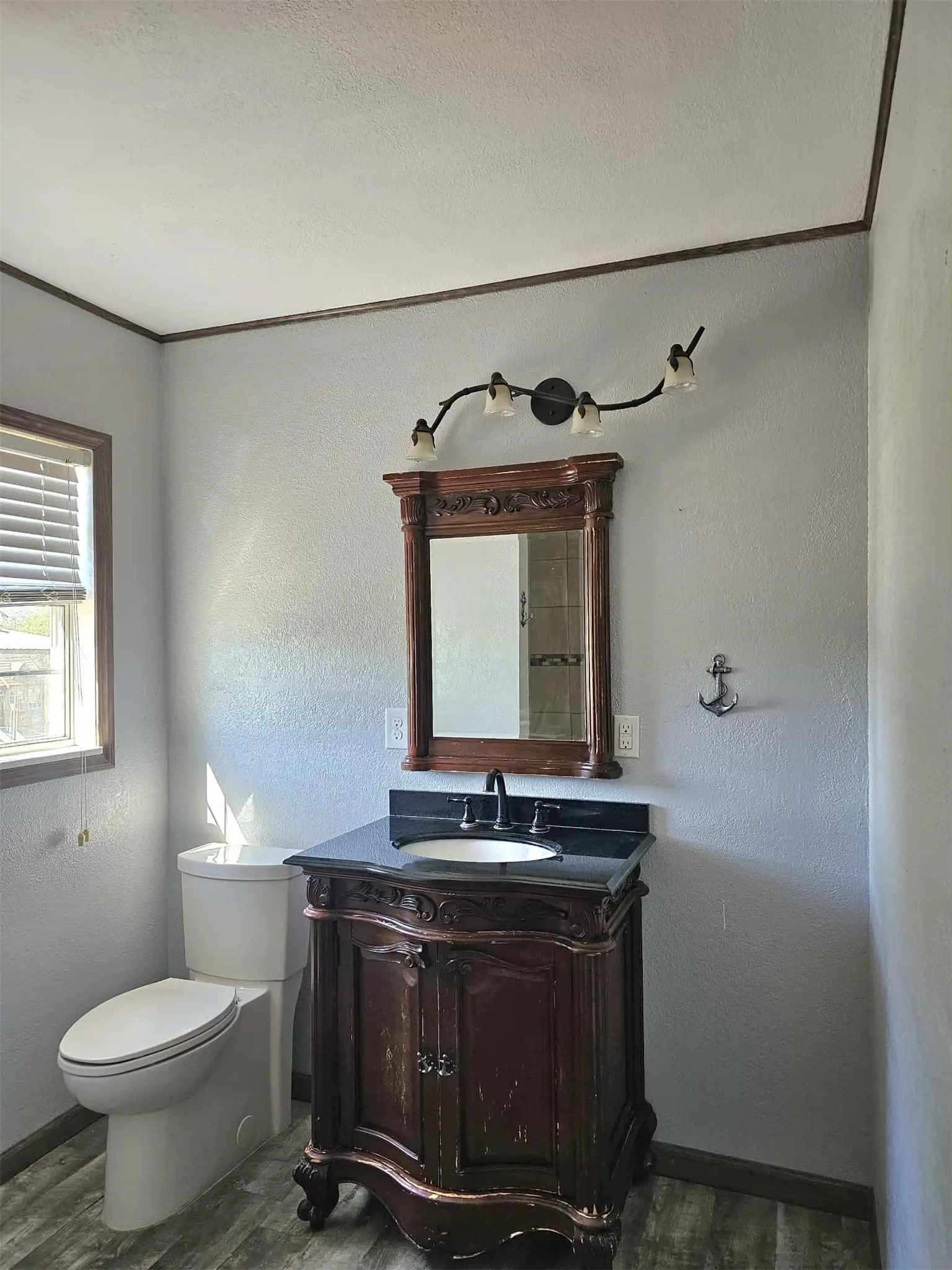 Bathroom with a textured wall, vanity, dark wood-style floors, and a textured ceiling