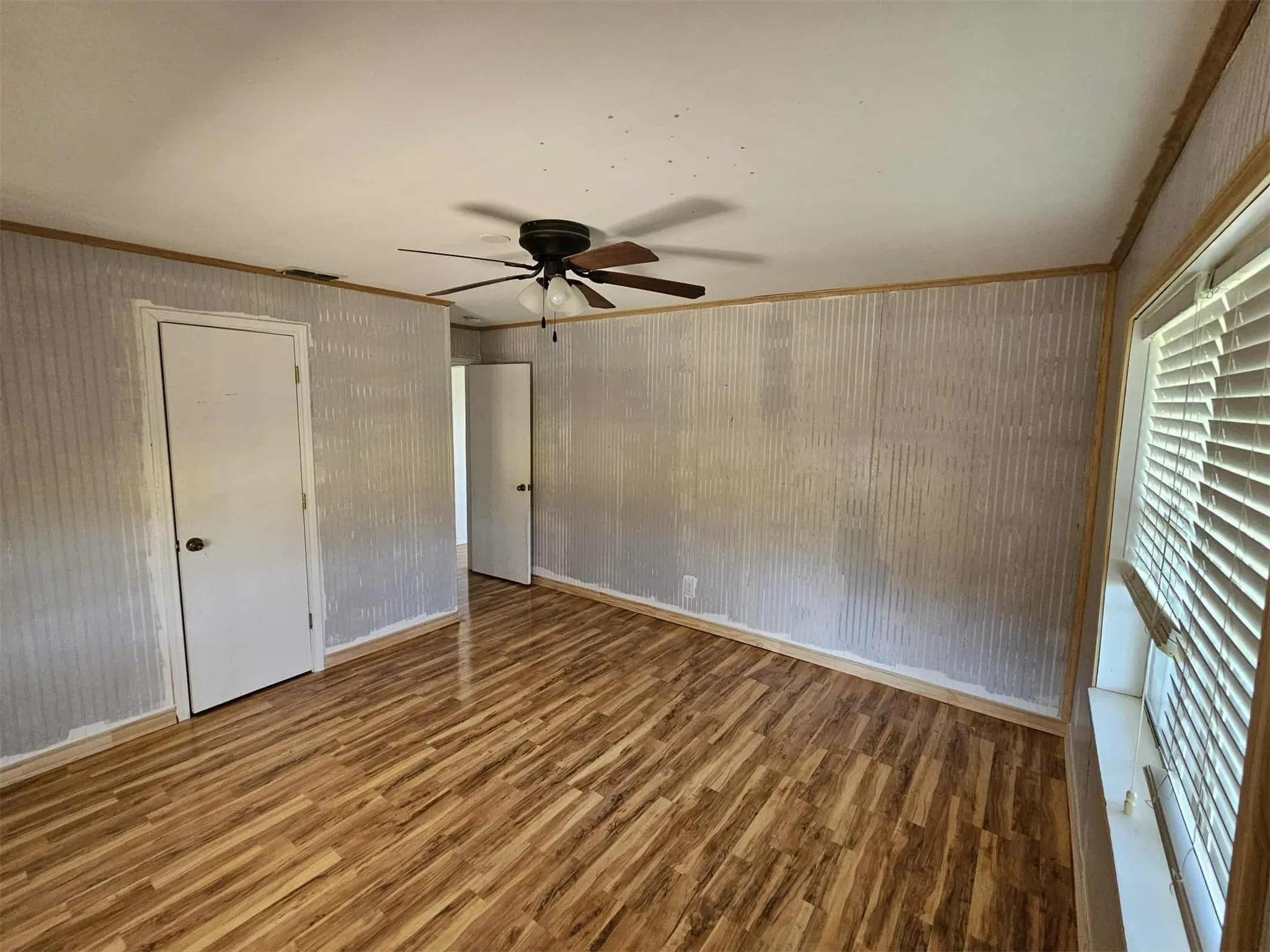 Unfurnished bedroom with wood finished floors, ornamental molding, and a ceiling fan