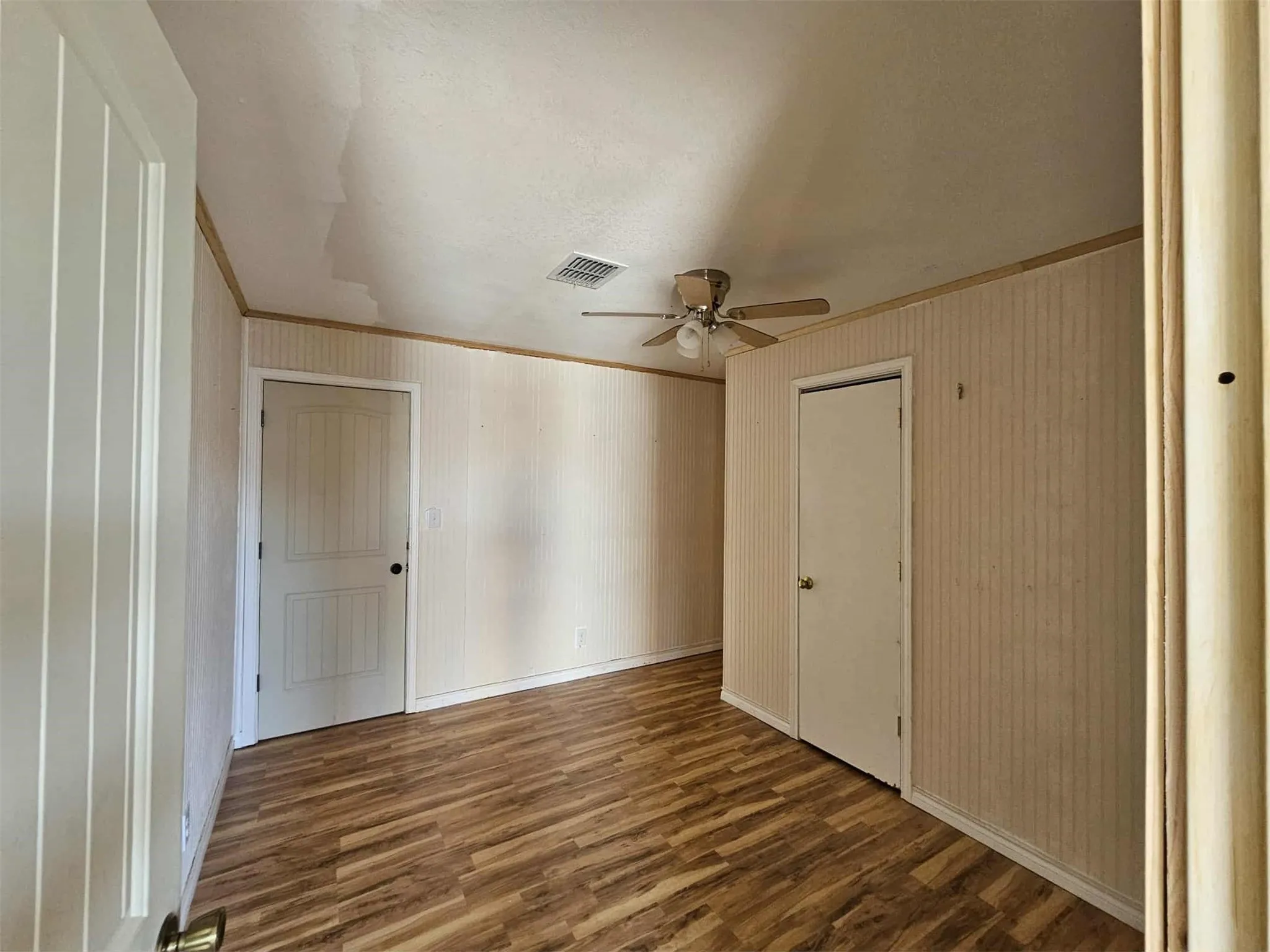 Unfurnished bedroom with wood finished floors, ornamental molding, ceiling fan, and a closet