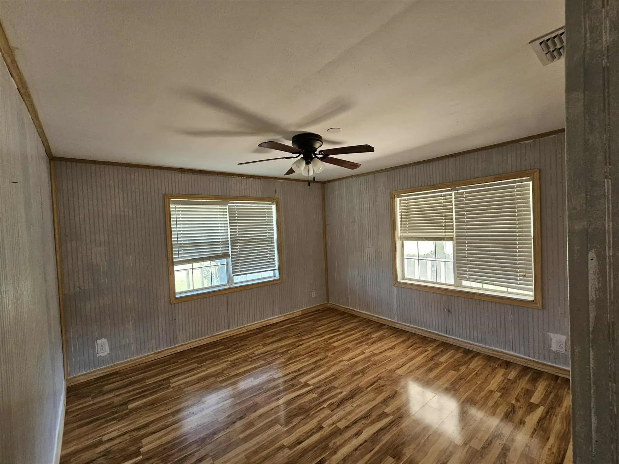 Empty room with dark wood-type flooring, ceiling fan, and ornamental molding