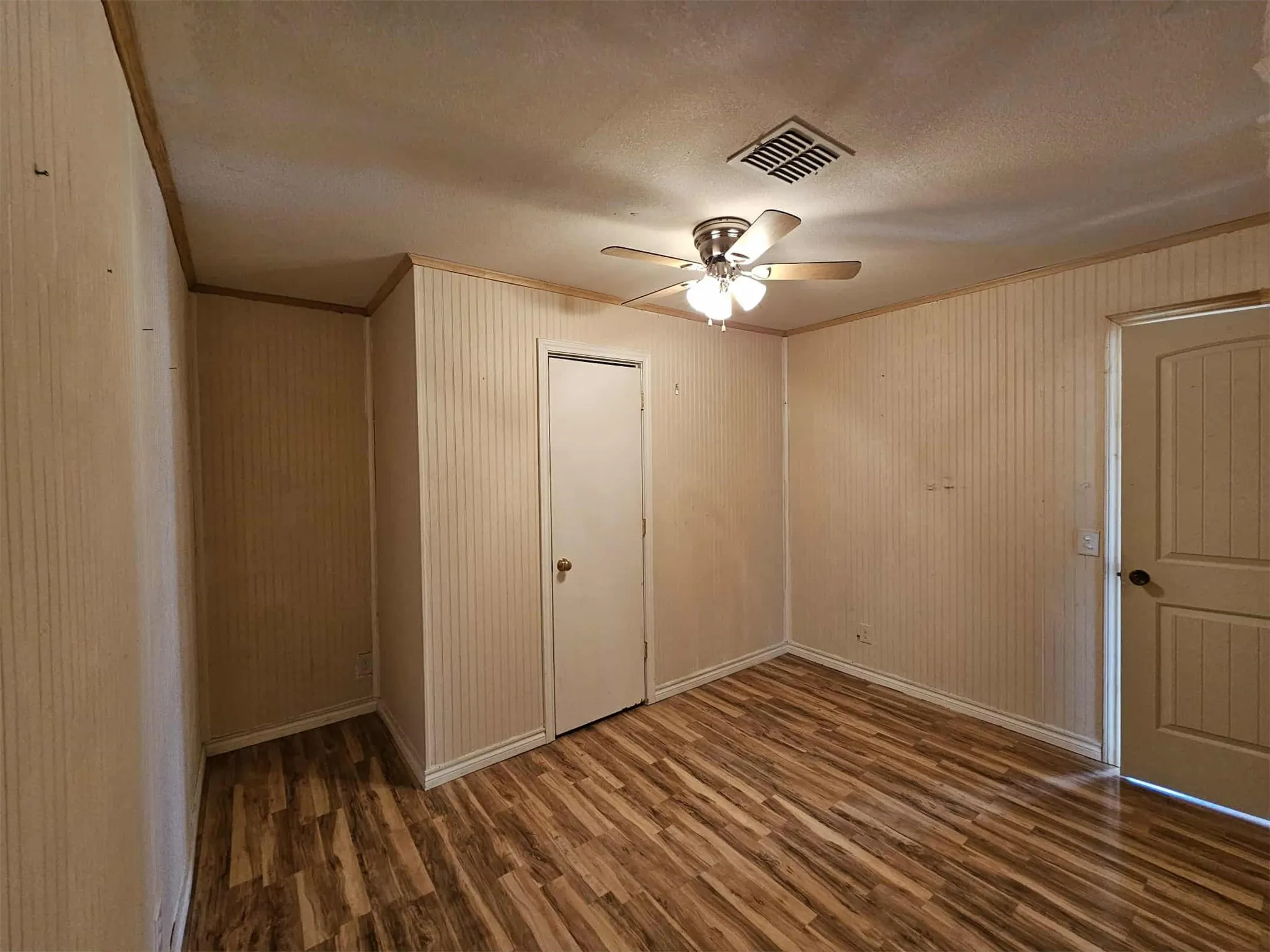 Unfurnished bedroom with crown molding, dark wood-style floors, a closet, ceiling fan, and a textured ceiling