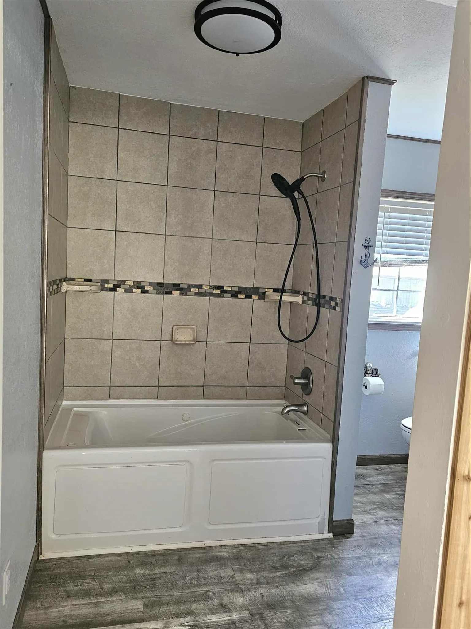 Bathroom with washtub / shower combination and dark wood-style flooring