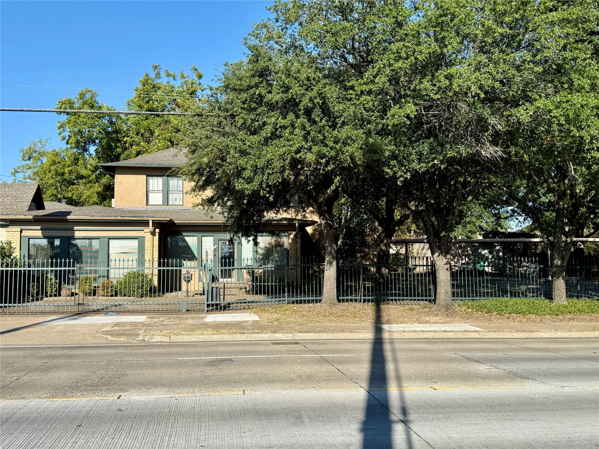 View of property hidden behind natural elements featuring a fenced front yard, roof with shingles, and stucco siding