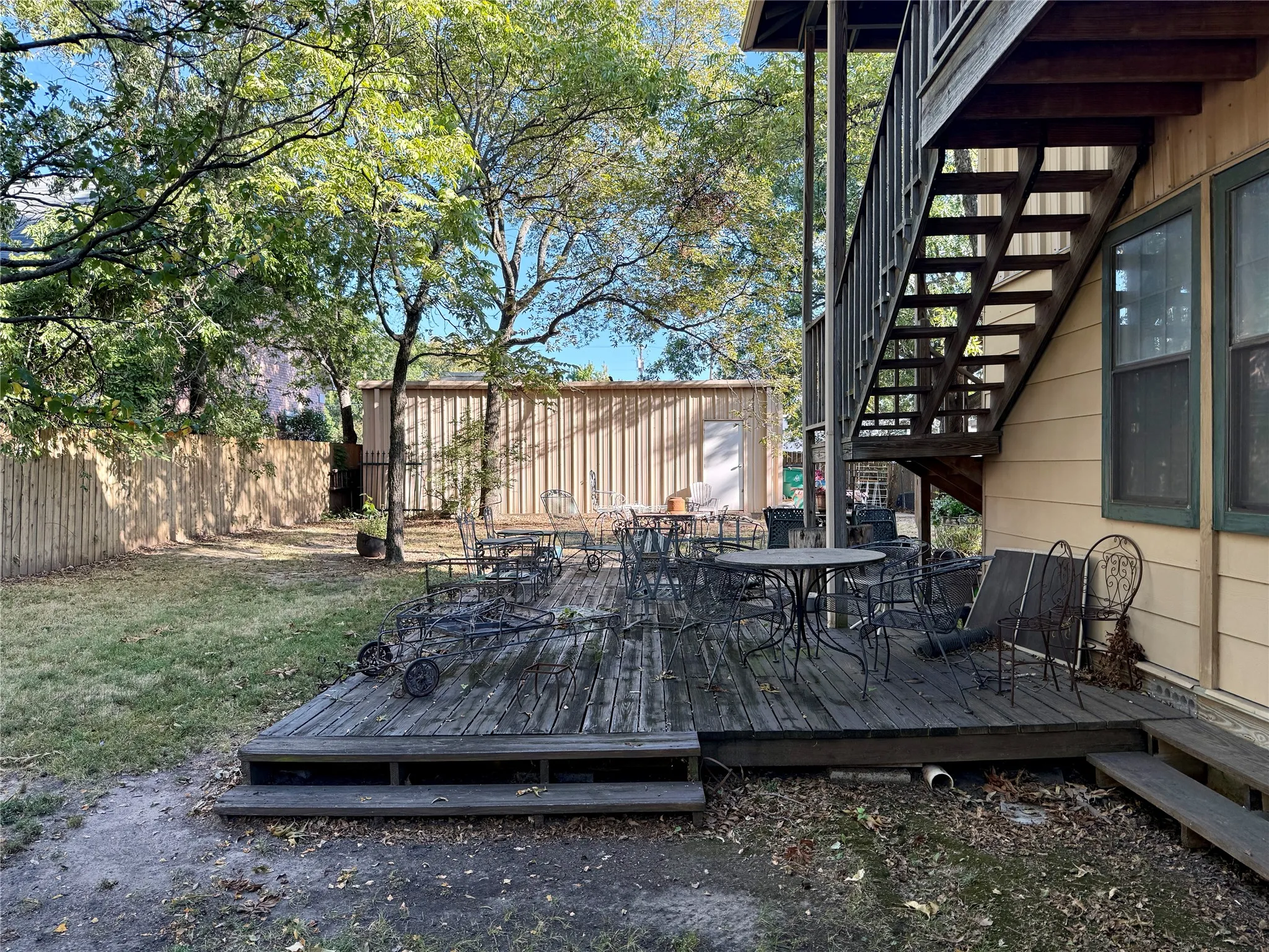 Wooden deck featuring outdoor dining space, stairs, and a fenced backyard