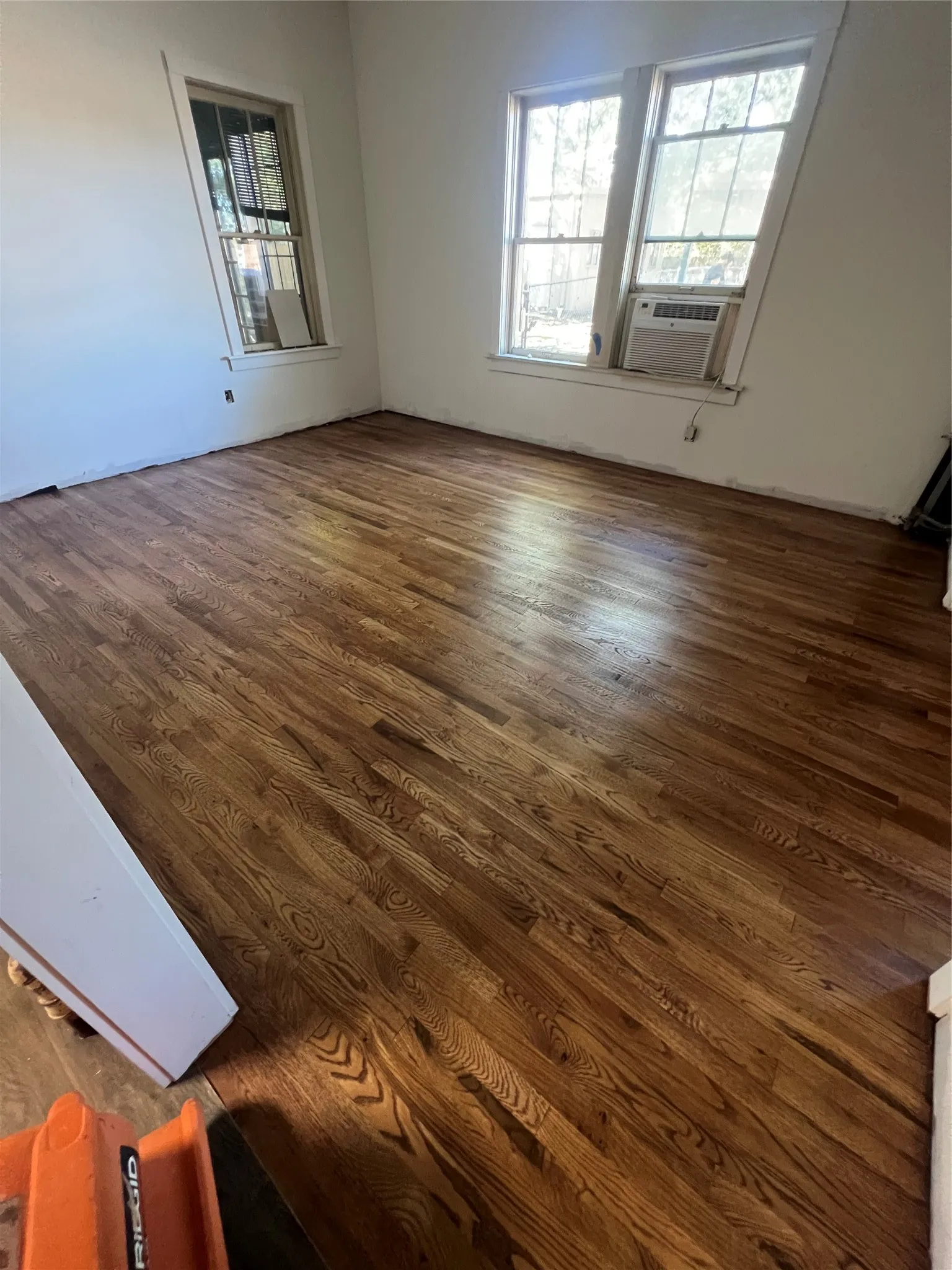 Hardwood flooring throughout, featuring multiple windows, and light-toned walls