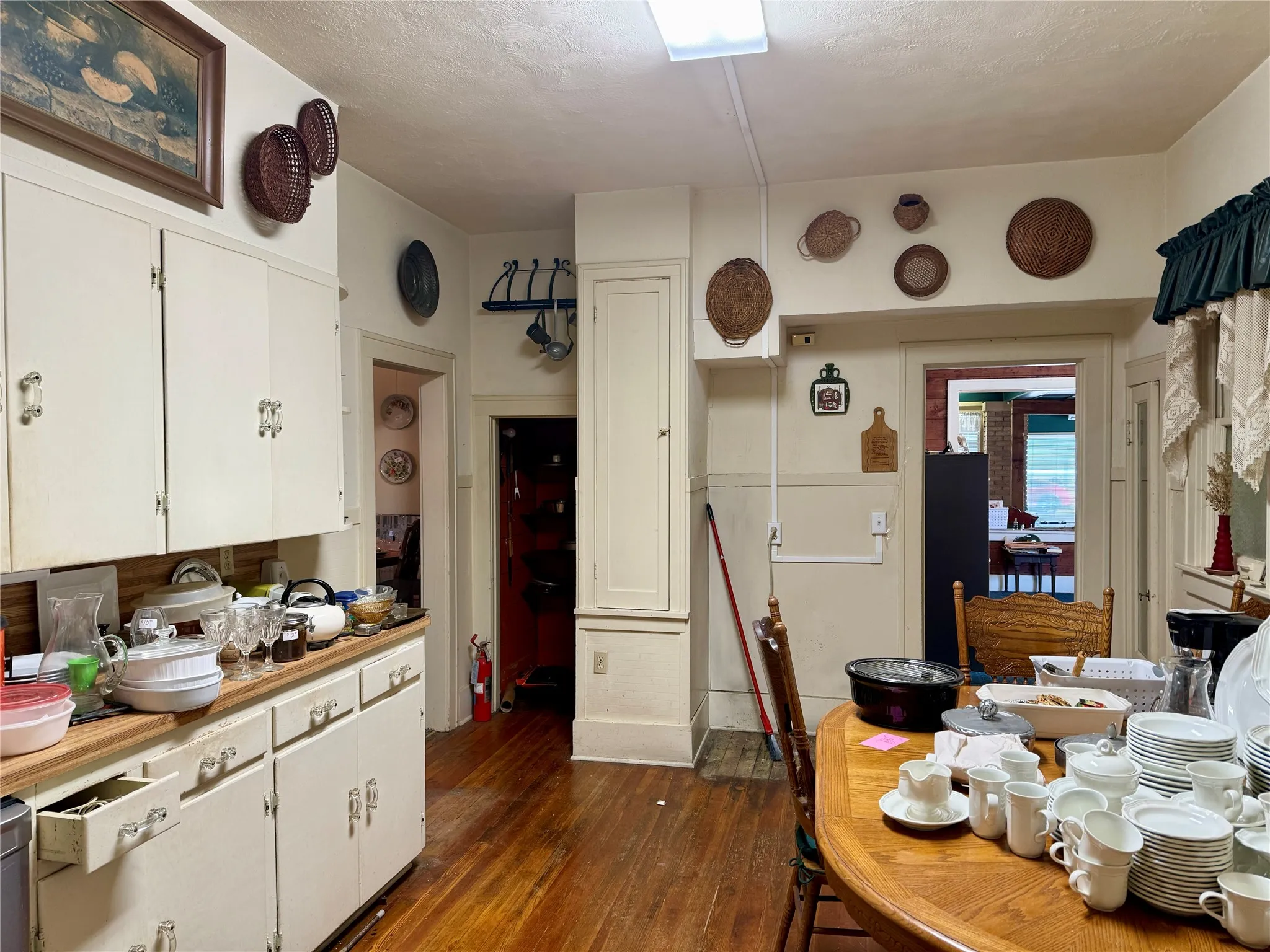 Kitchen with dark wood-type flooring, white cabinetry, and light countertops