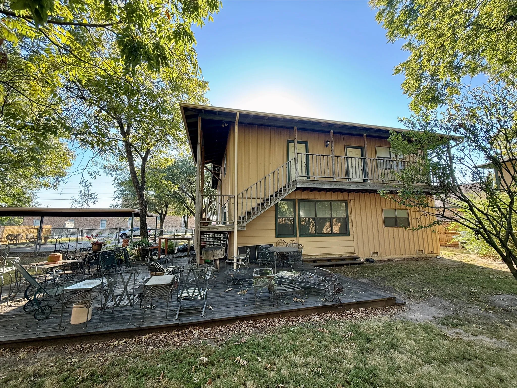 Back of property featuring stairway, a wooden deck, a balcony, a yard, and board and batten siding