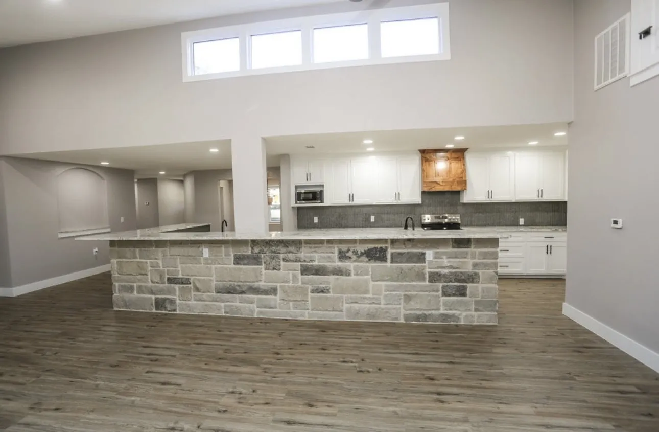 Kitchen with a high ceiling, a large island, white cabinetry, premium range hood, and a breakfast bar area