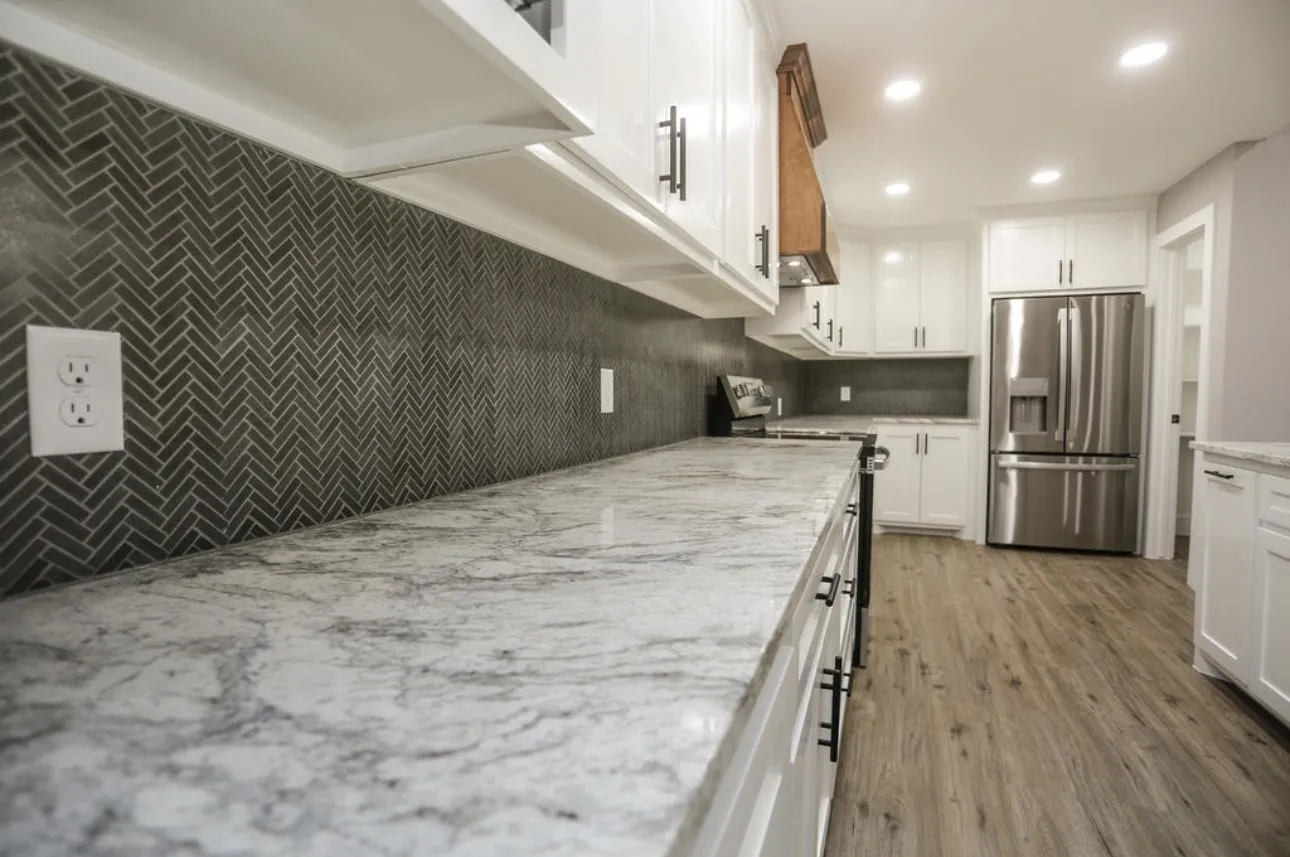 Kitchen with white cabinetry, stainless steel appliances, light stone counters, recessed lighting, and wood finished floors