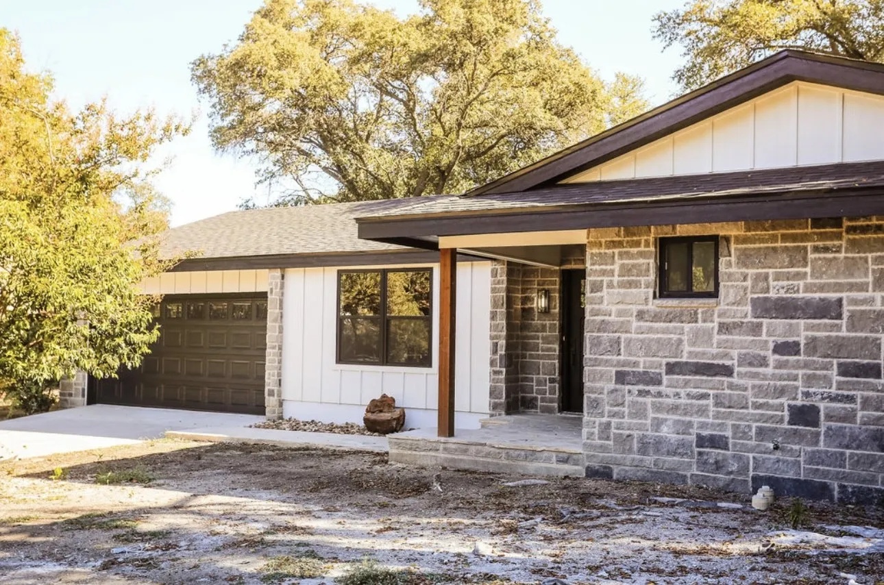 View of front of home with board and batten siding, covered porch, an attached garage, and driveway