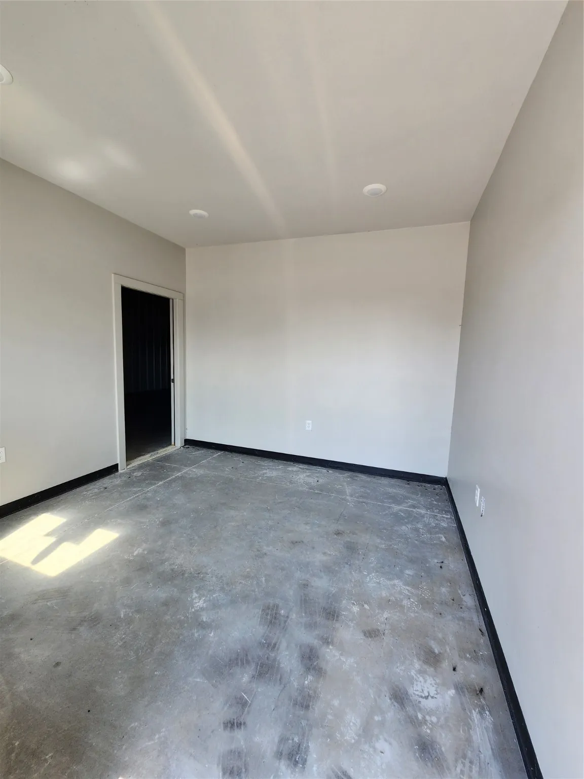 Unfurnished room with unfinished concrete floors and baseboards