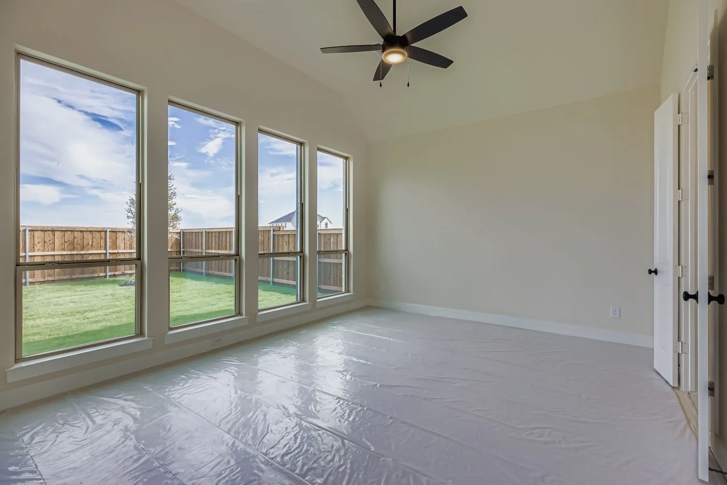 Empty room with vaulted ceiling and ceiling fan