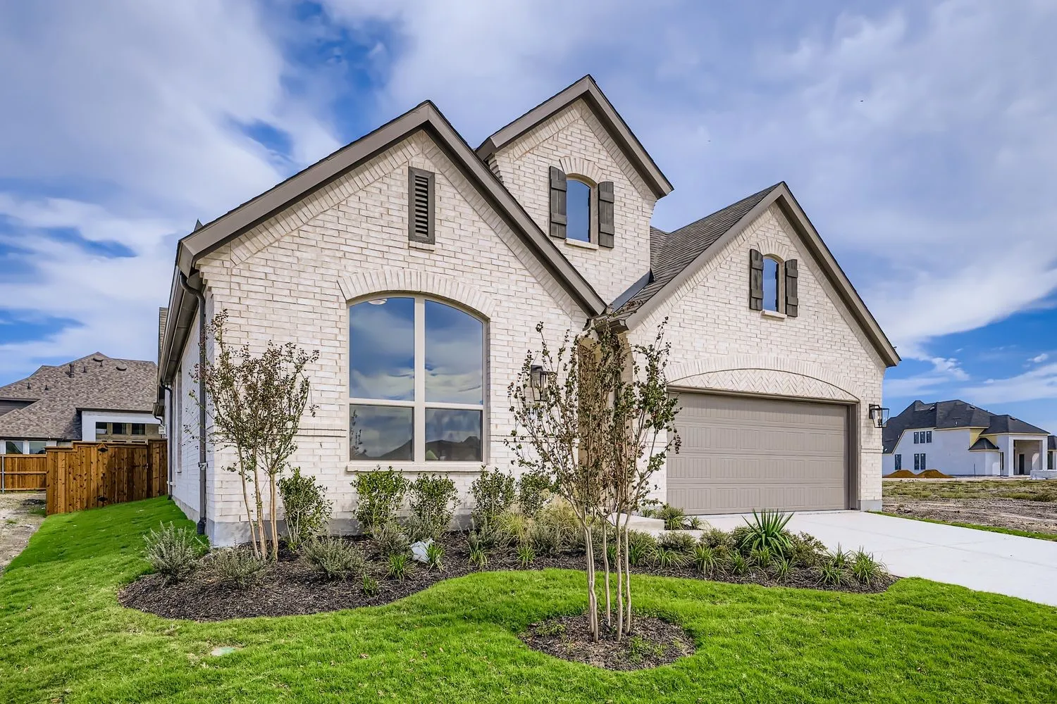 French provincial home with brick siding, driveway, and stone siding