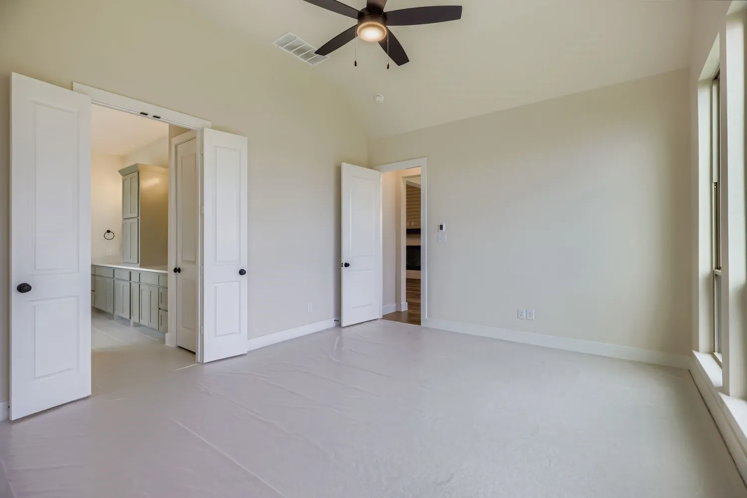 Unfurnished bedroom featuring lofted ceiling, light carpet, a ceiling fan, and connected bathroom
