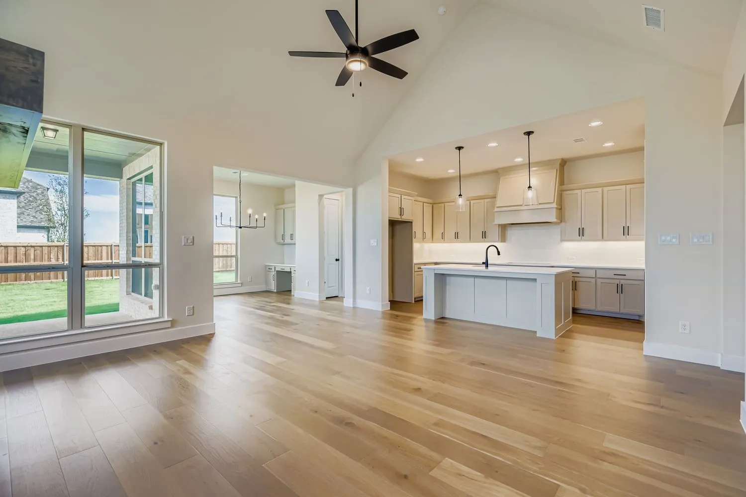 Unfurnished living room featuring high vaulted ceiling, light wood-style flooring, a chandelier, ceiling fan, and recessed lighting