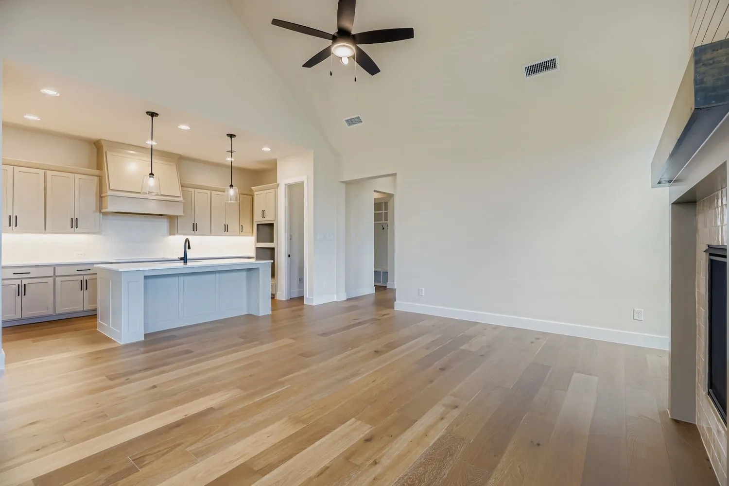 Unfurnished living room with light wood finished floors, high vaulted ceiling, a fireplace, recessed lighting, and a ceiling fan