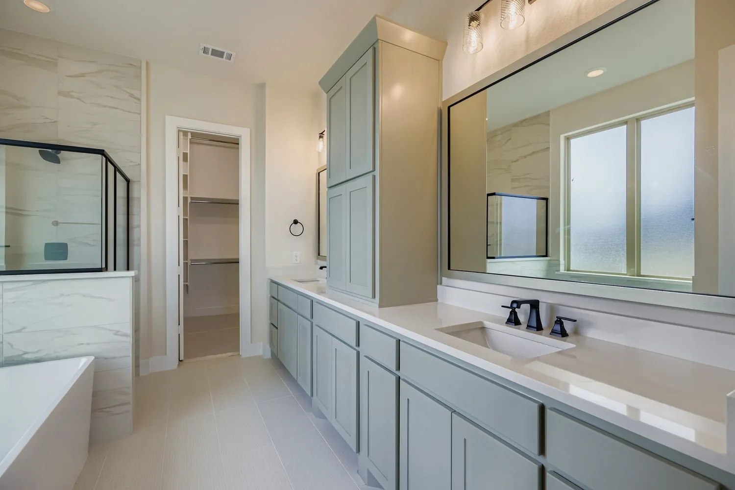 Full bathroom featuring double vanity, a freestanding tub, a walk in closet, a marble finish shower, and recessed lighting
