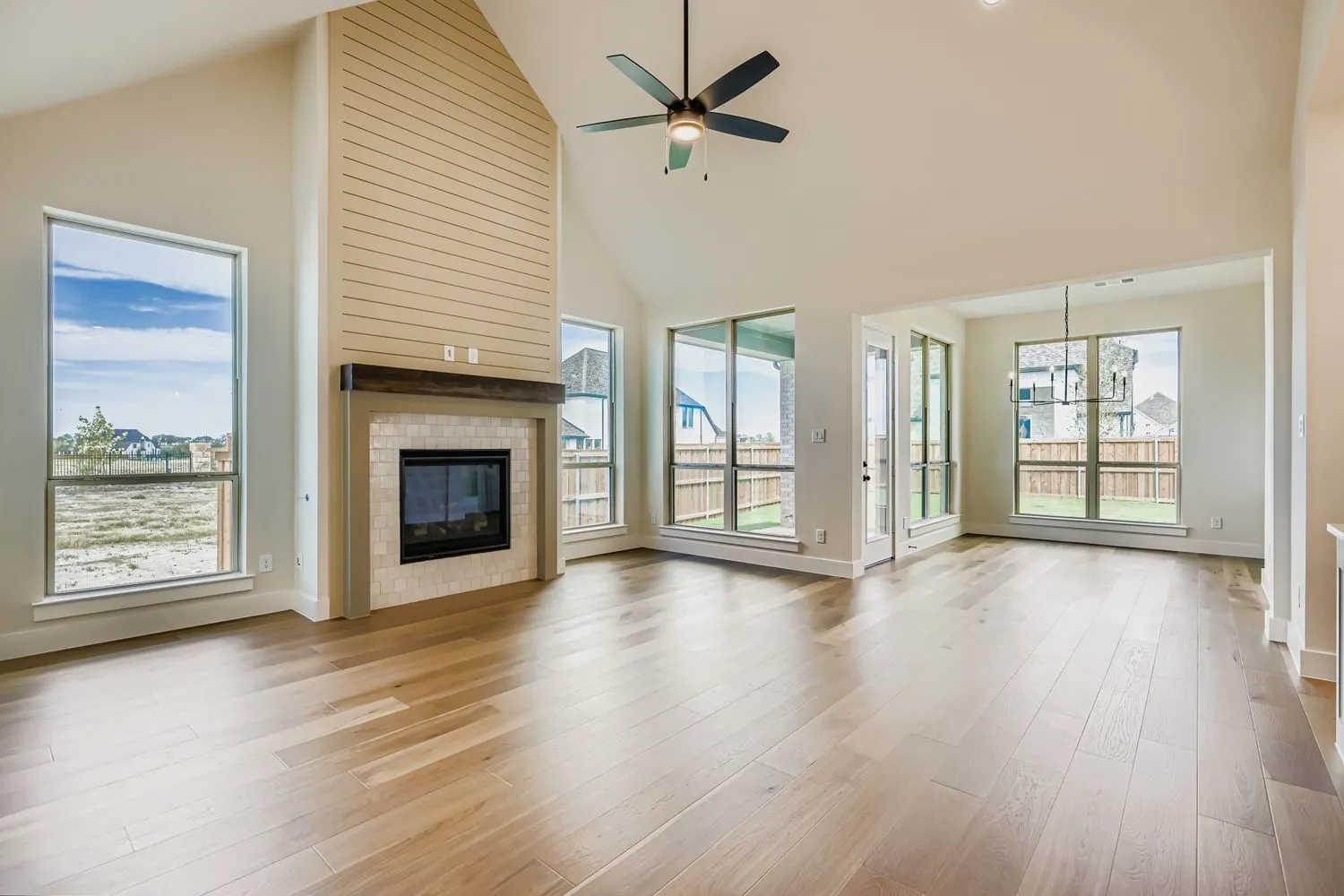 Unfurnished living room with high vaulted ceiling, a fireplace, light wood-type flooring, and ceiling fan