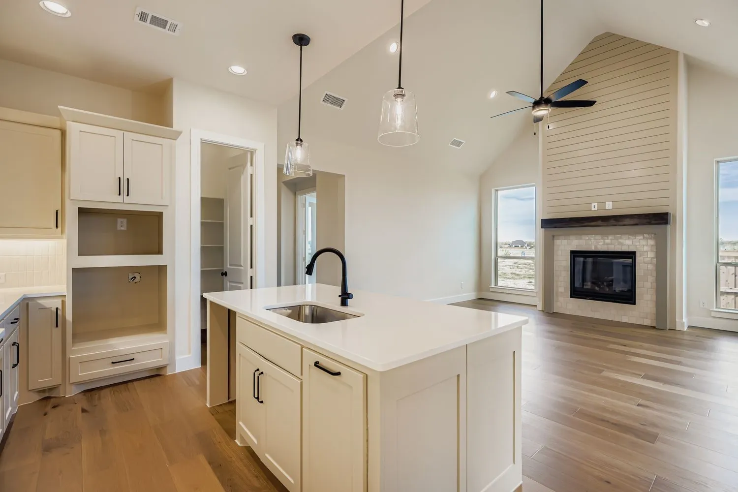 Kitchen featuring a center island with sink, high vaulted ceiling, open floor plan, decorative light fixtures, and light wood-style floors