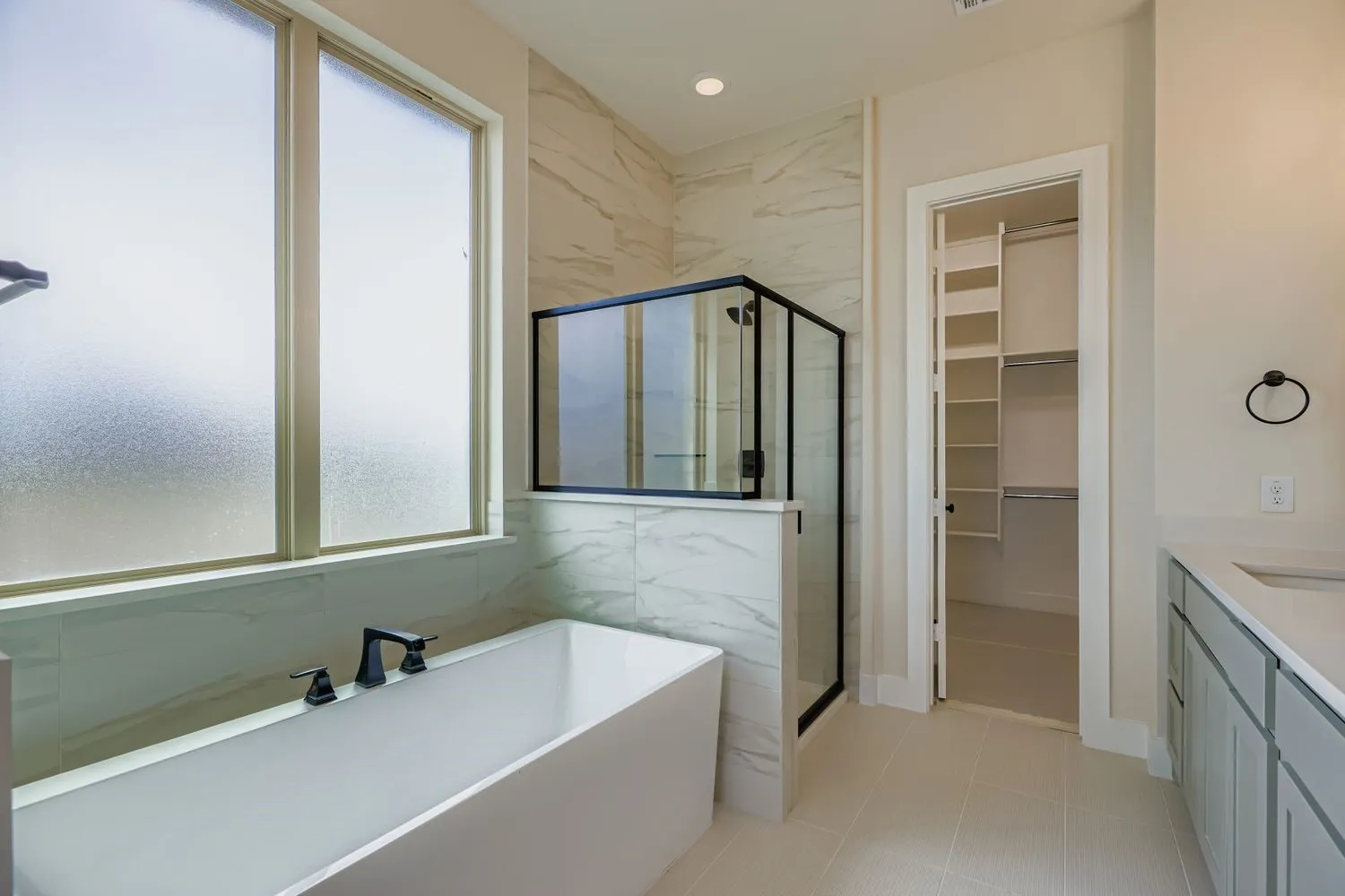 Bathroom with a freestanding tub, a marble finish shower, vanity, a walk in closet, and light tile patterned flooring
