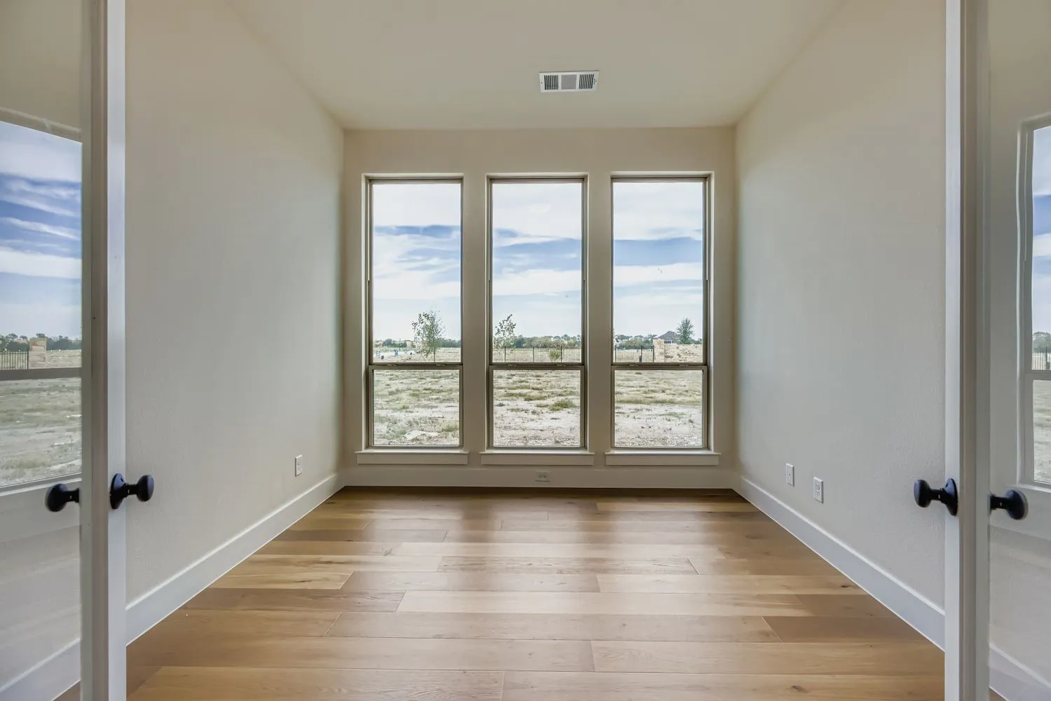 Empty room with light wood-style floors and french doors