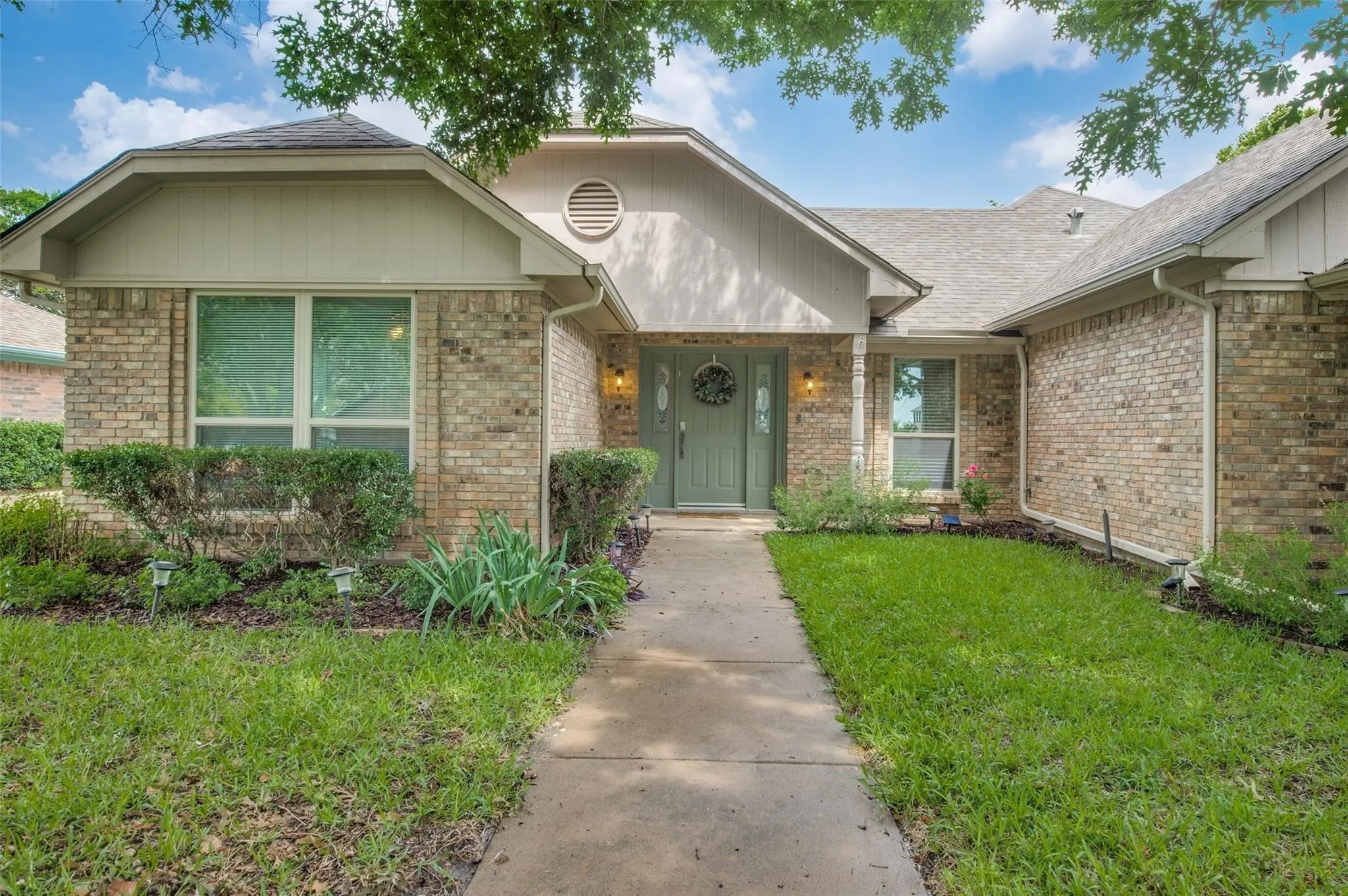 Property entrance with a yard, brick siding, and a shingled roof