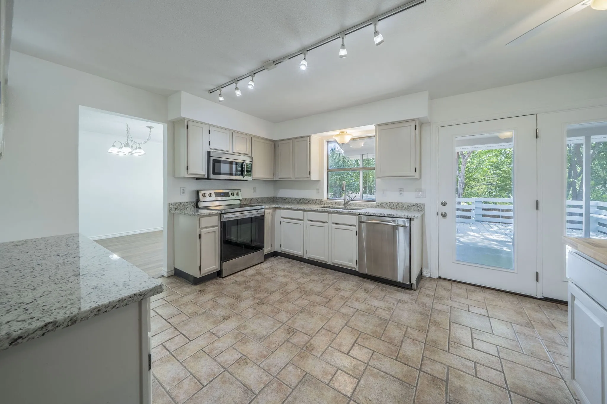 Kitchen with stainless steel appliances, light stone countertops and track lighting