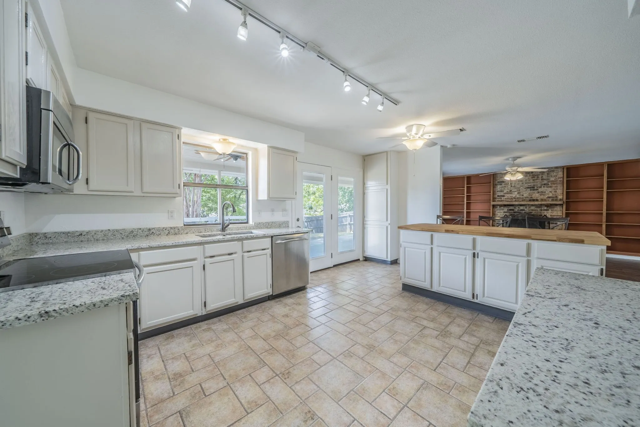 Kitchen with a ceiling fan, stainless steel appliances, and white cabinets. This open living-dining and kitchen area overlooks the magnificent patio and deck area.