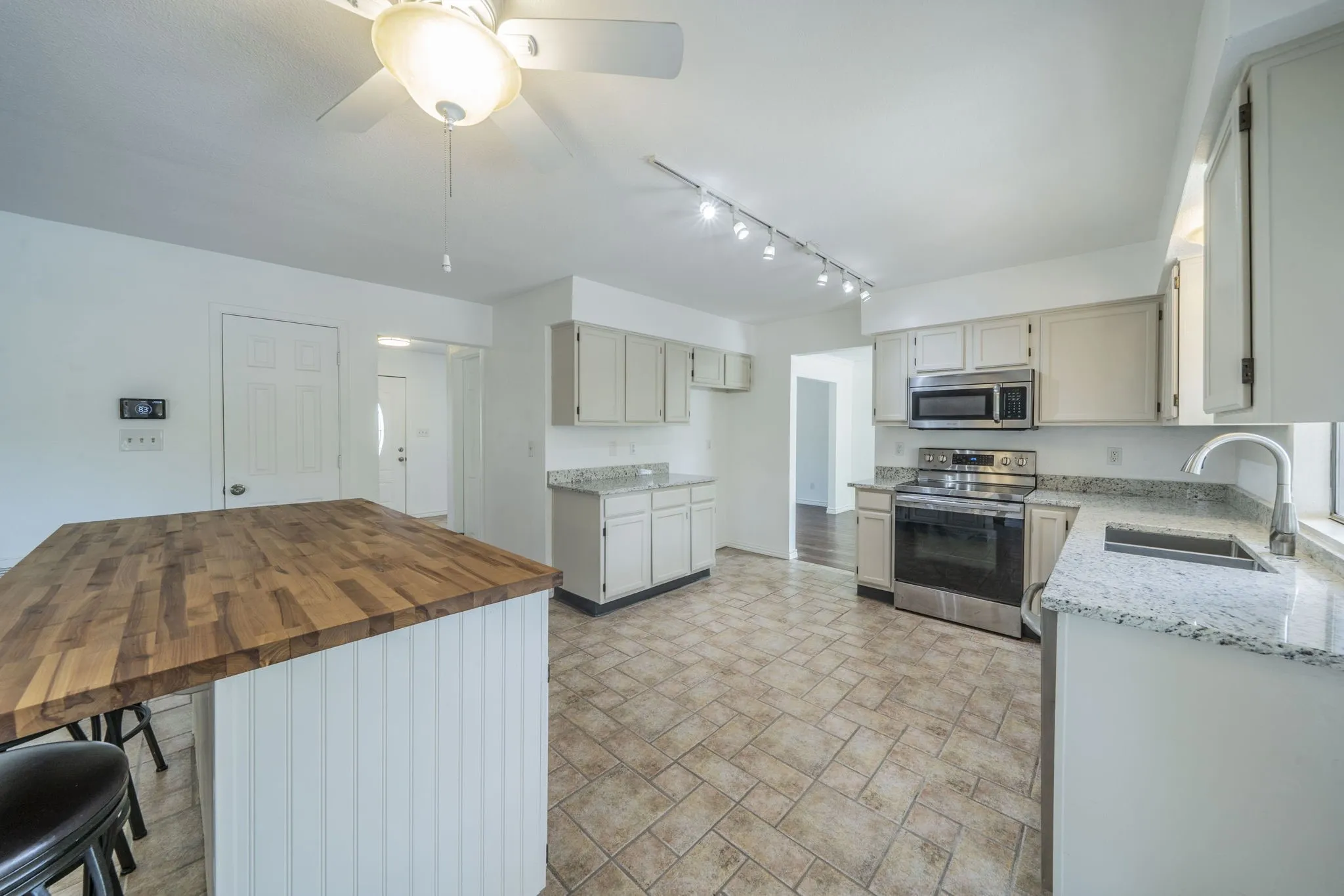 Kitchen with appliances with stainless steel finishes, light stone counters, a breakfast bar area, a ceiling fan, and rail lighting