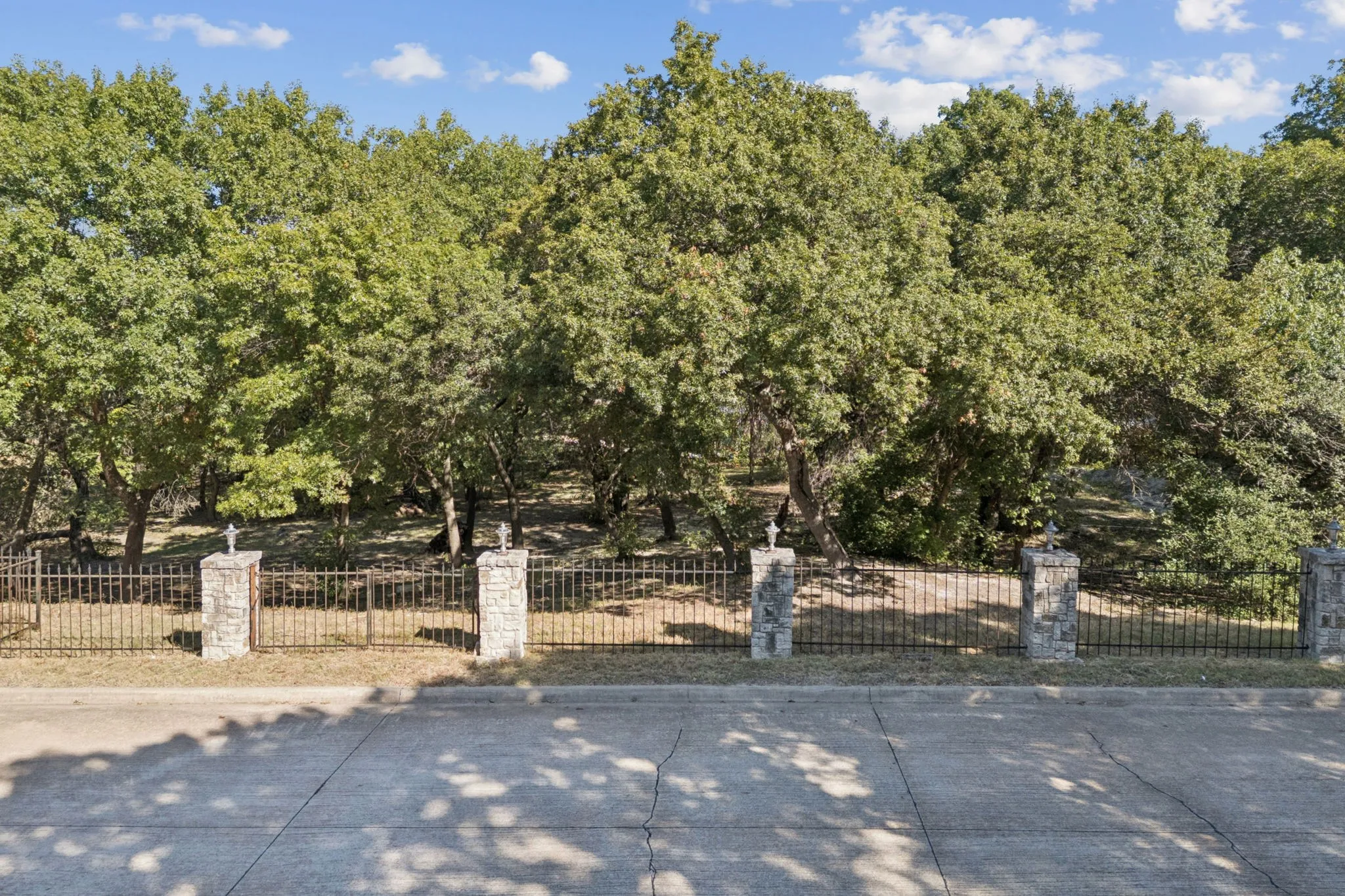 View of the front of the property with the stone columns and wrought iron fence.