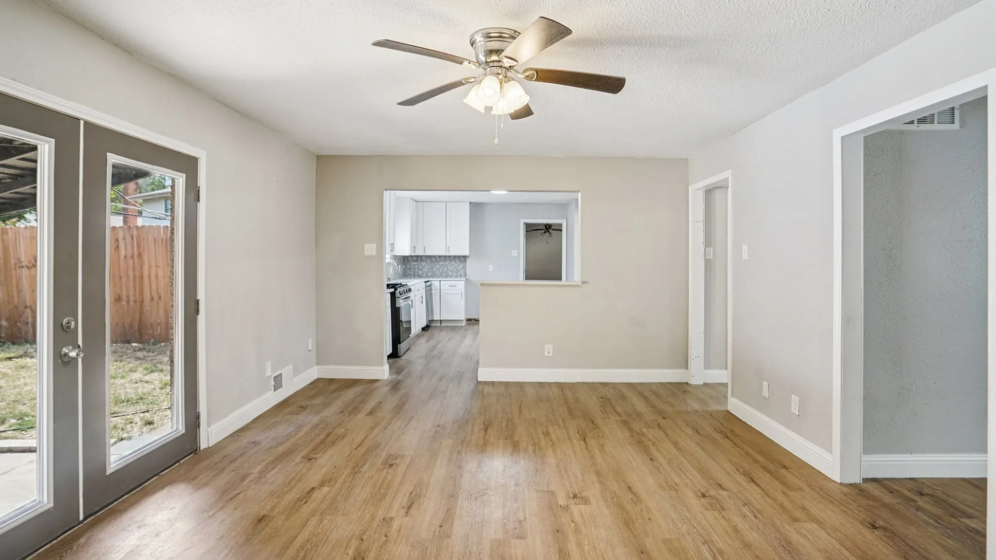 Unfurnished living room featuring french doors, light wood-style flooring, and a ceiling fan