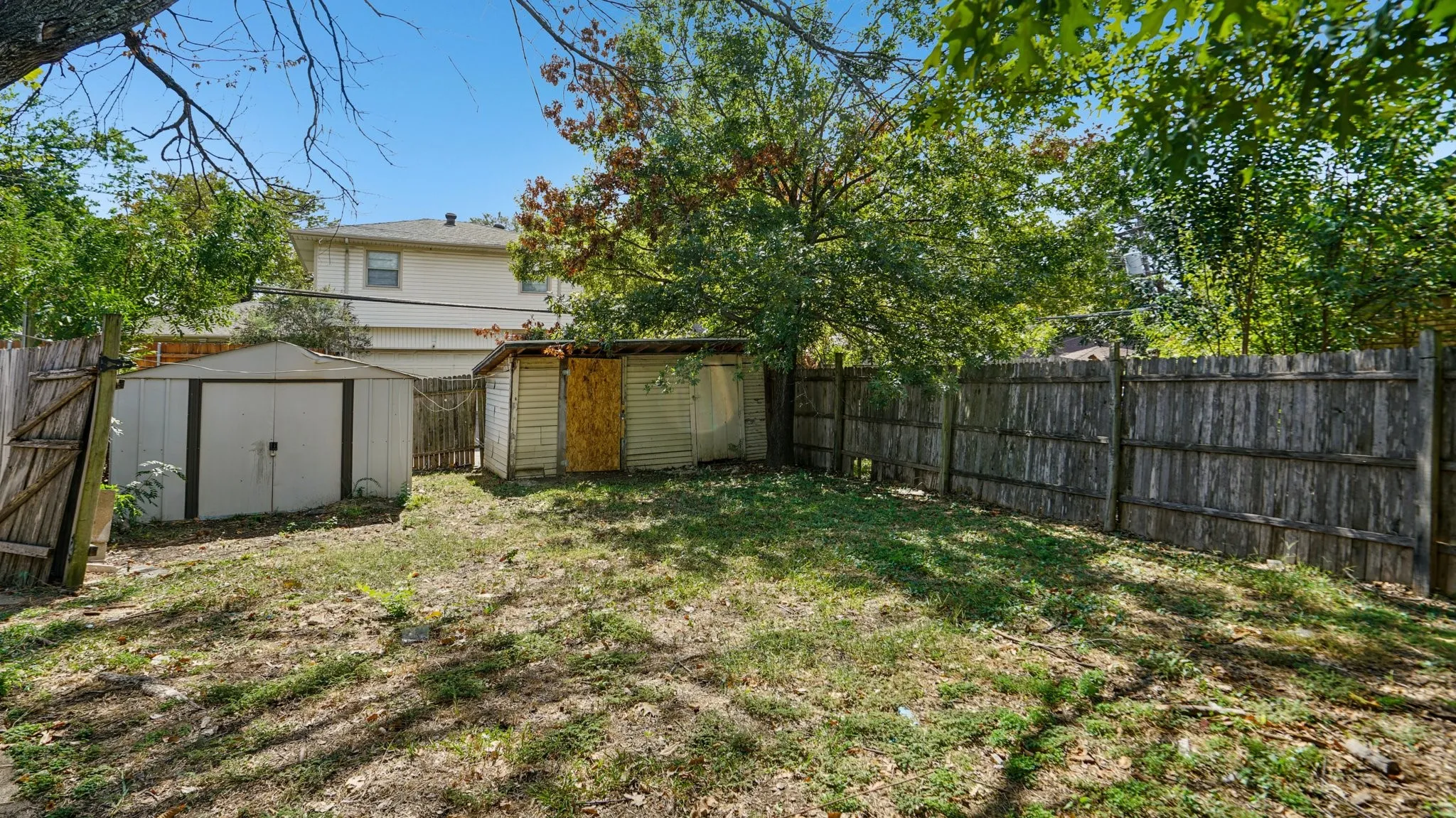 Fenced backyard featuring a storage unit