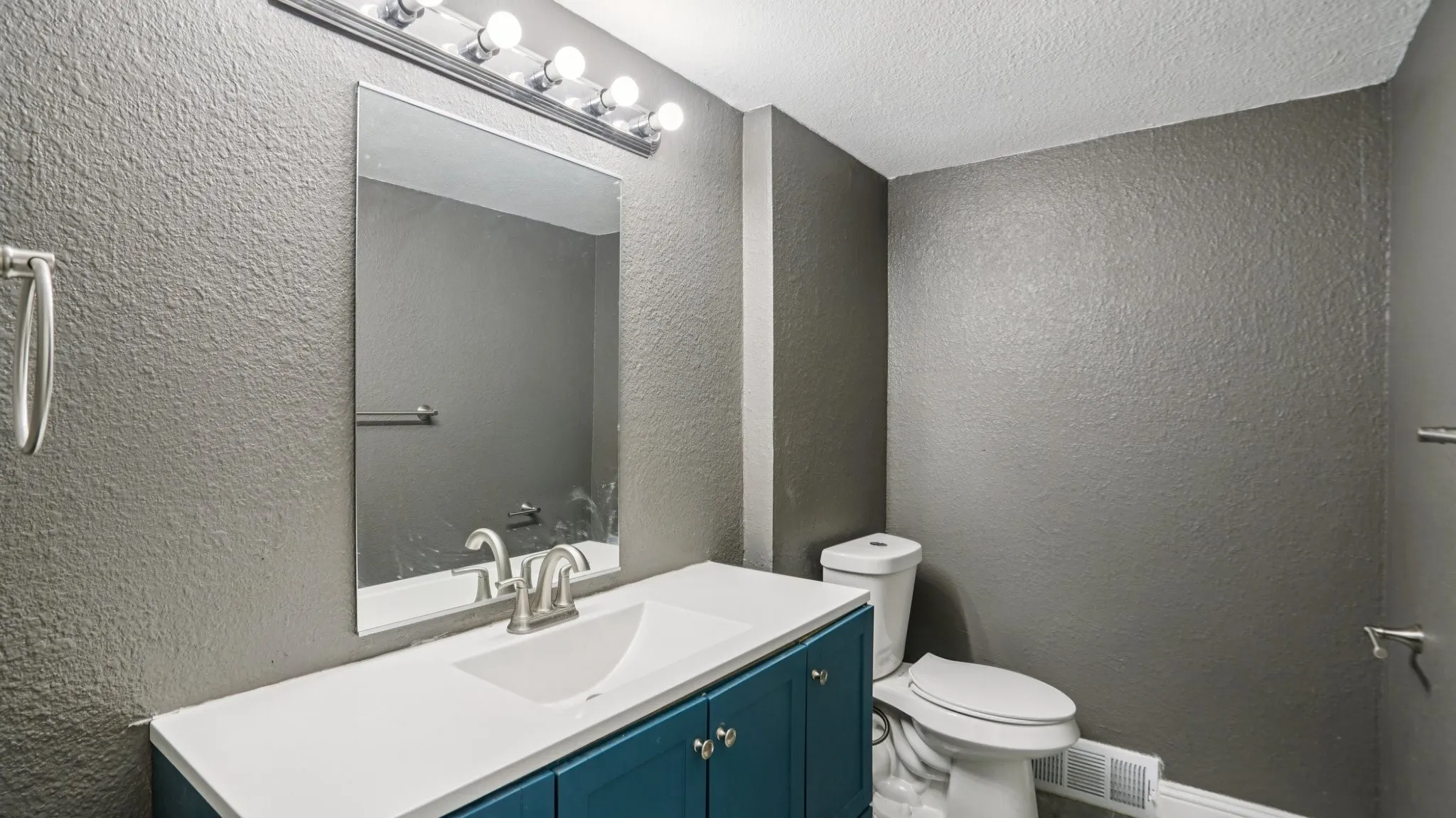 Bathroom featuring a textured wall, vanity, and a textured ceiling