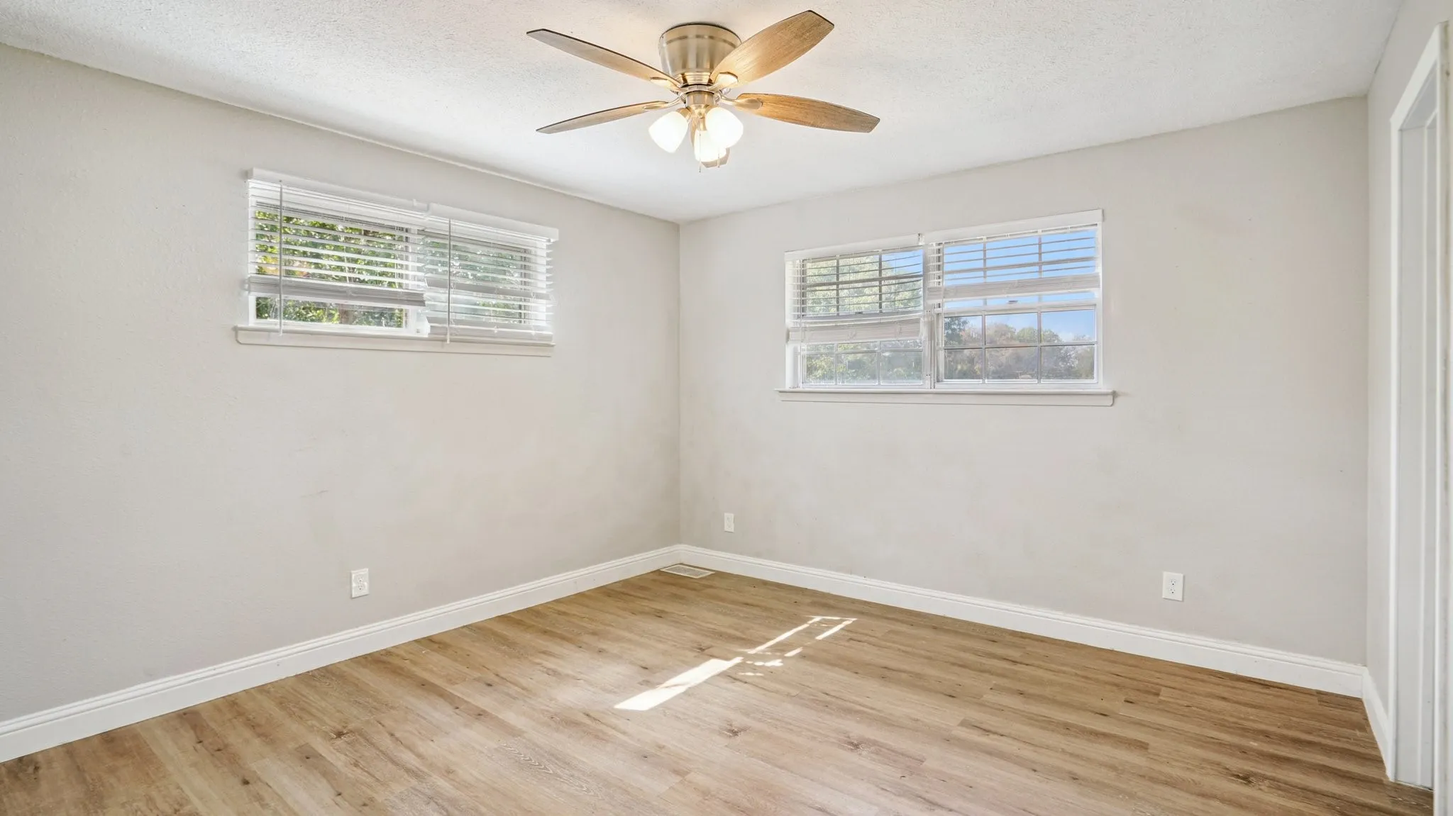 Unfurnished bedroom featuring ceiling fan, multiple windows, light wood finished floors, and a textured ceiling
