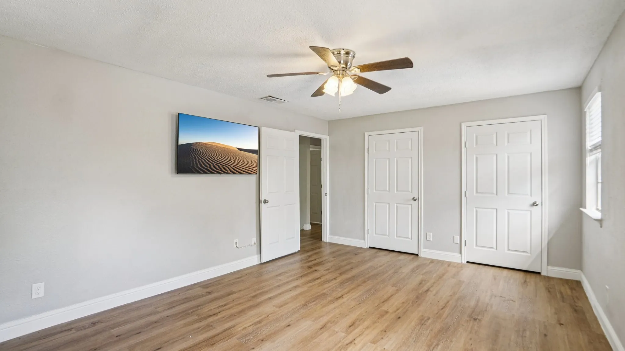 Unfurnished bedroom with two closets, light wood-style flooring, and a ceiling fan