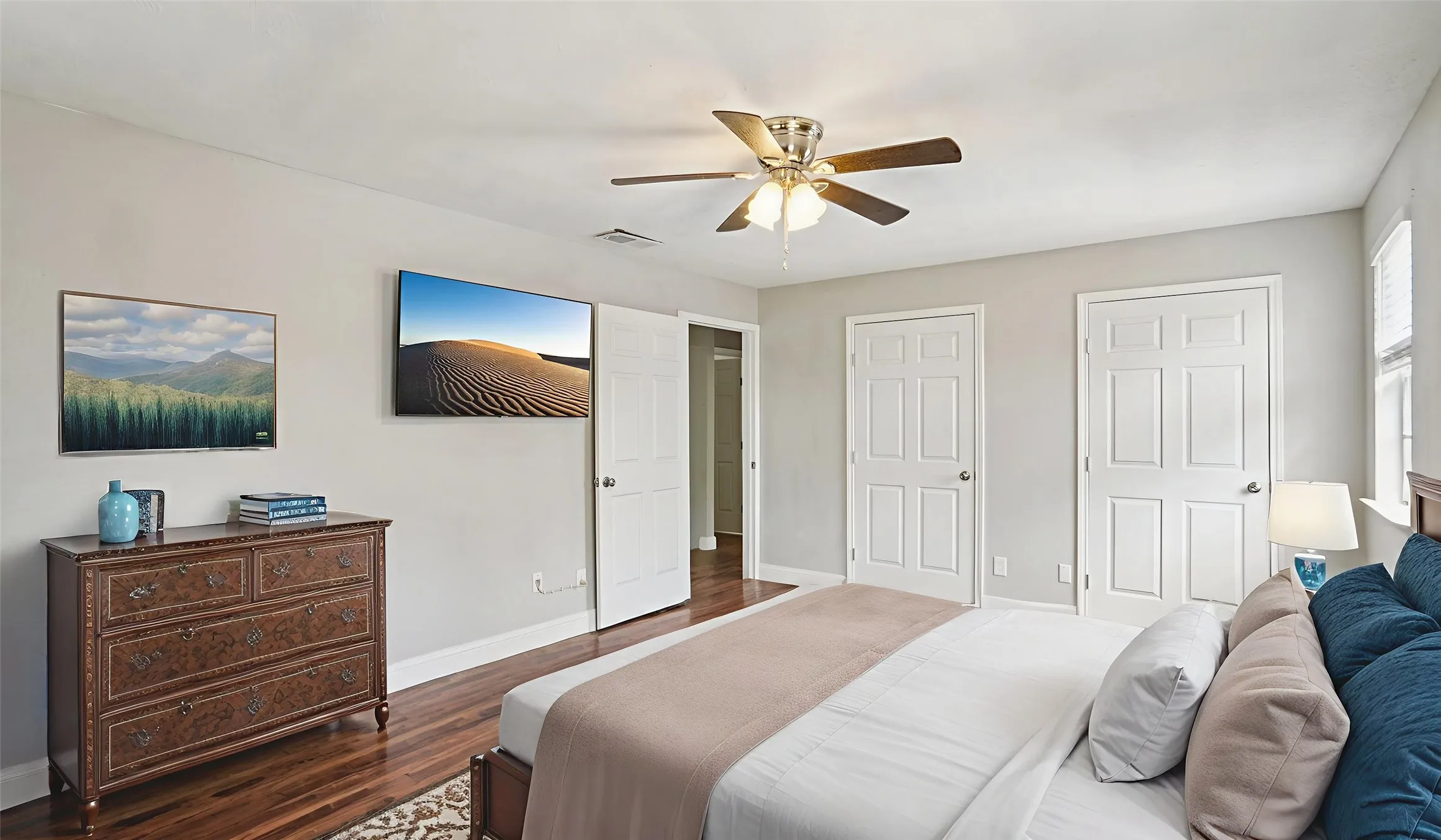 Bedroom featuring multiple closets, dark wood-style floors, and a ceiling fan. Virtual Staged
