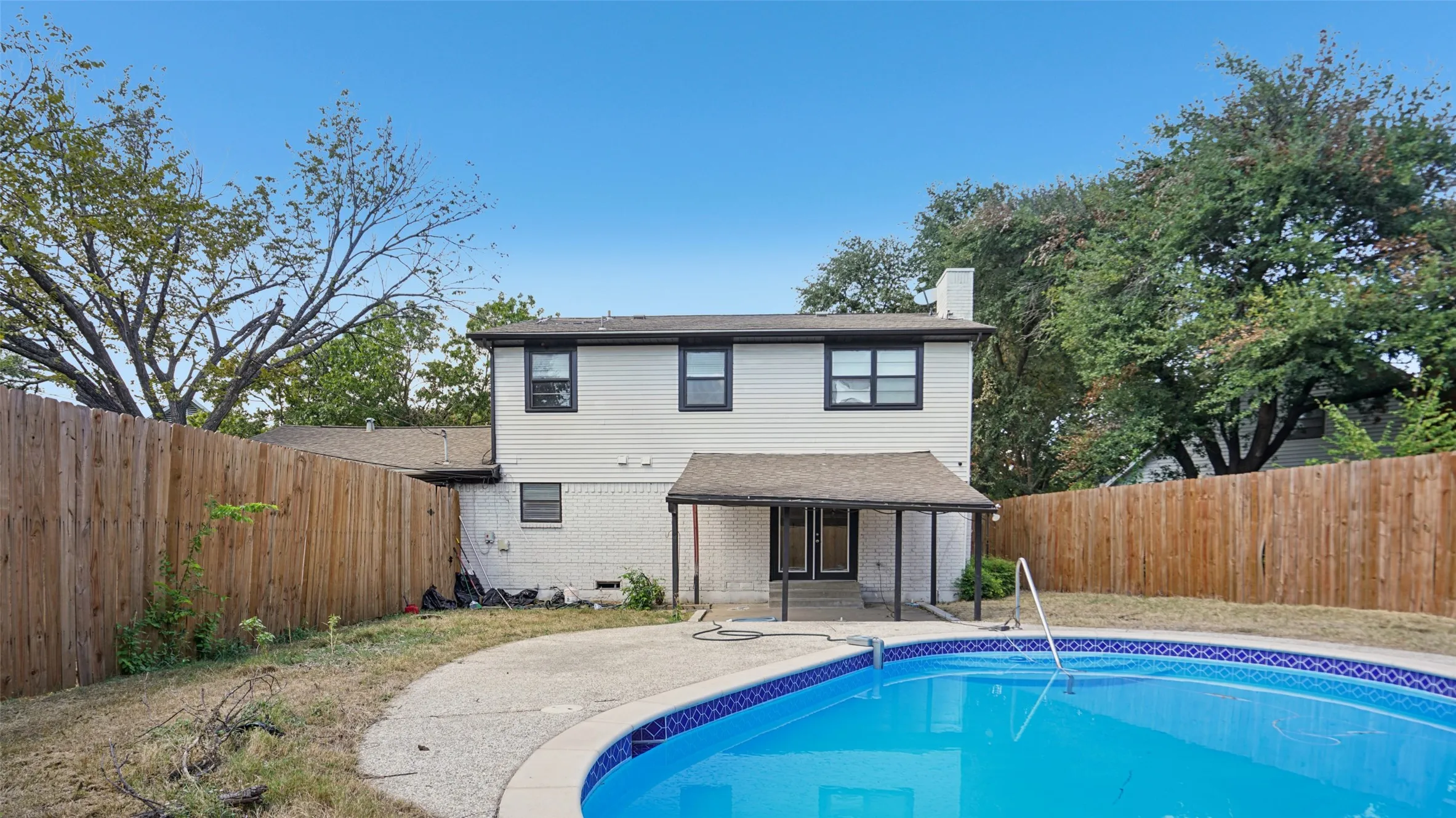 Rear view of property with a chimney, brick siding, a fenced backyard, and a patio area