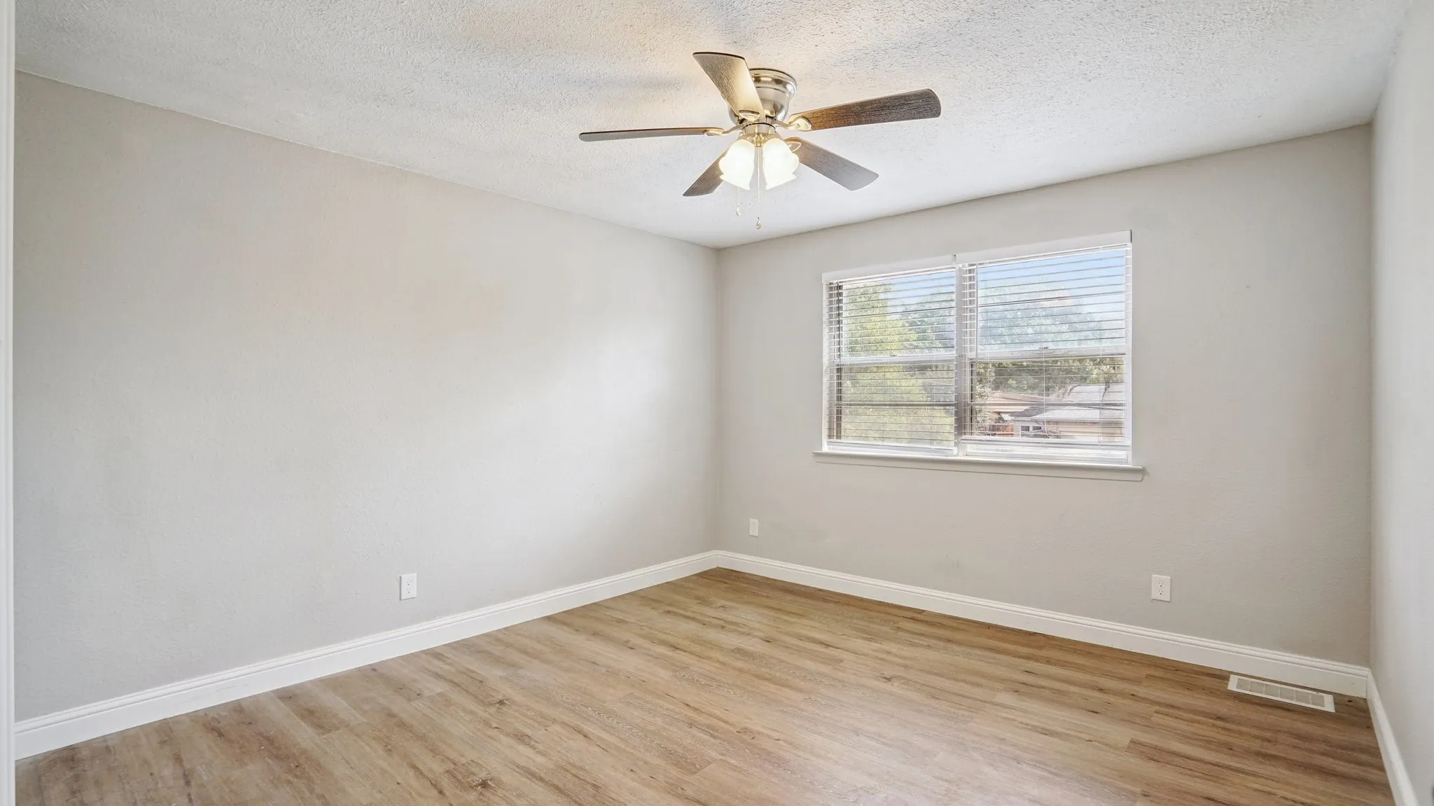 Unfurnished room featuring light wood finished floors, a textured ceiling, and a ceiling fan